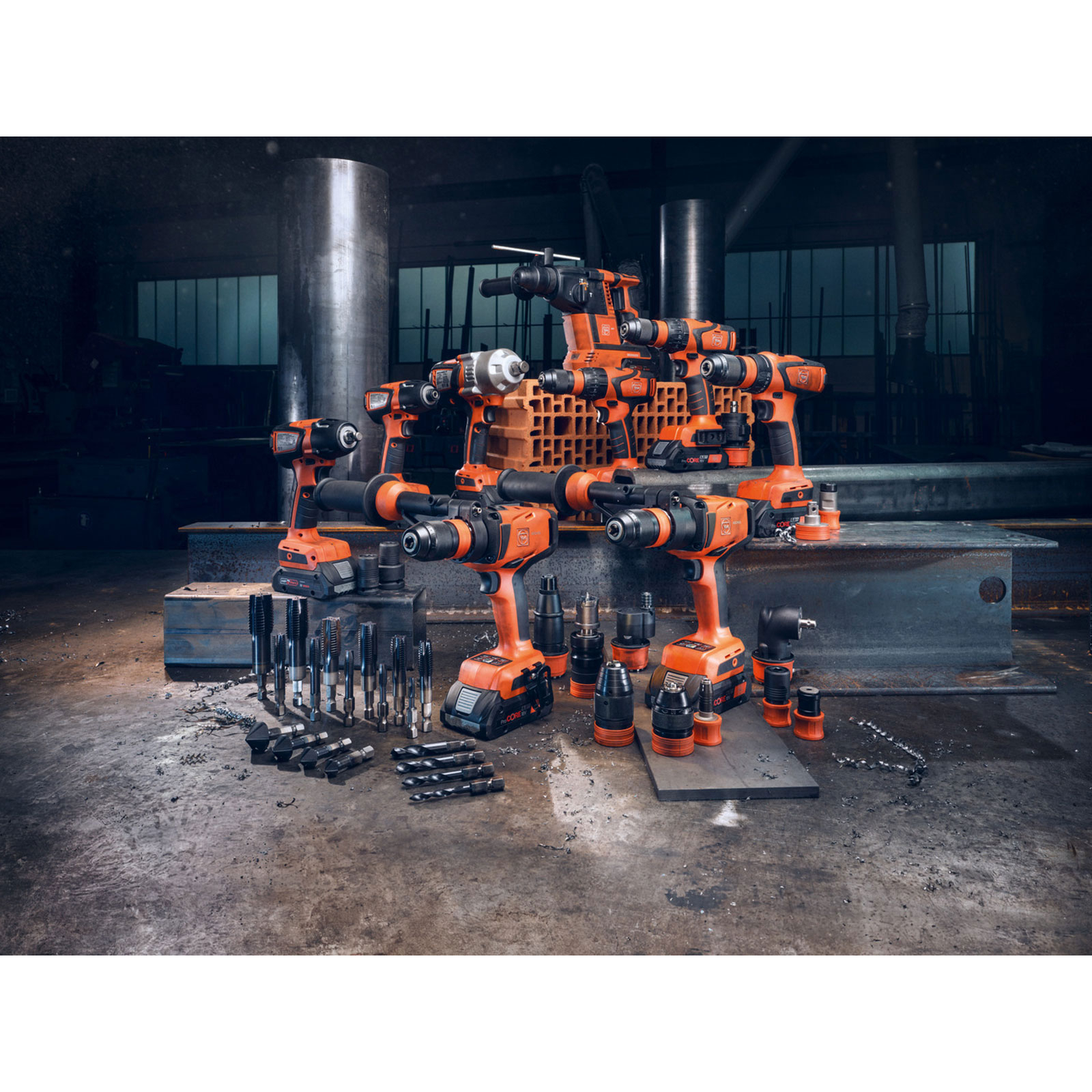 Mehrere orangefarbene Bohrer und Werkzeuge auf einem industriellen Boden.