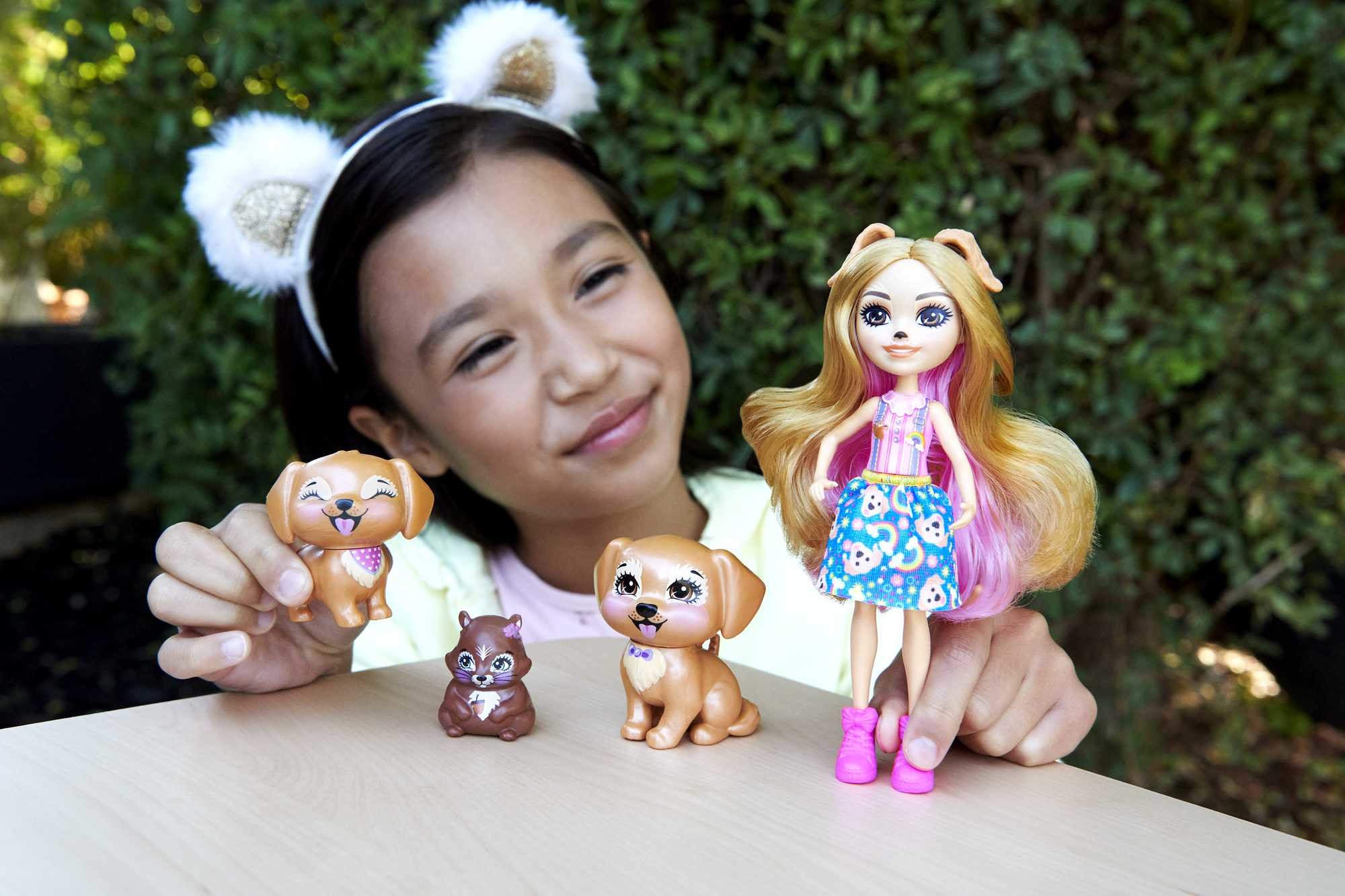 Ein Mädchen mit Ohrenhaarreifen hält Spielzeugtiere und eine Puppe.