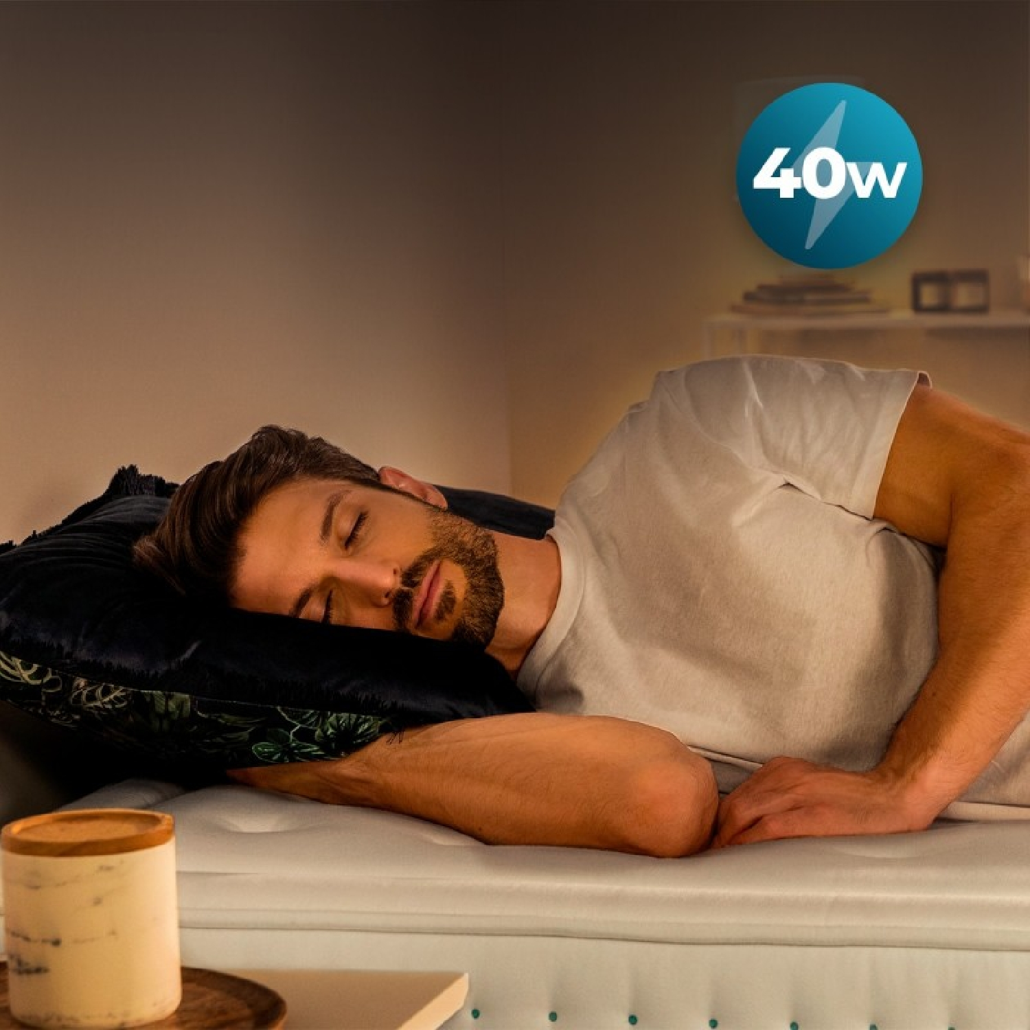 Un hombre duerme en una cama blanca. Se ve un indicador azul de 40w.