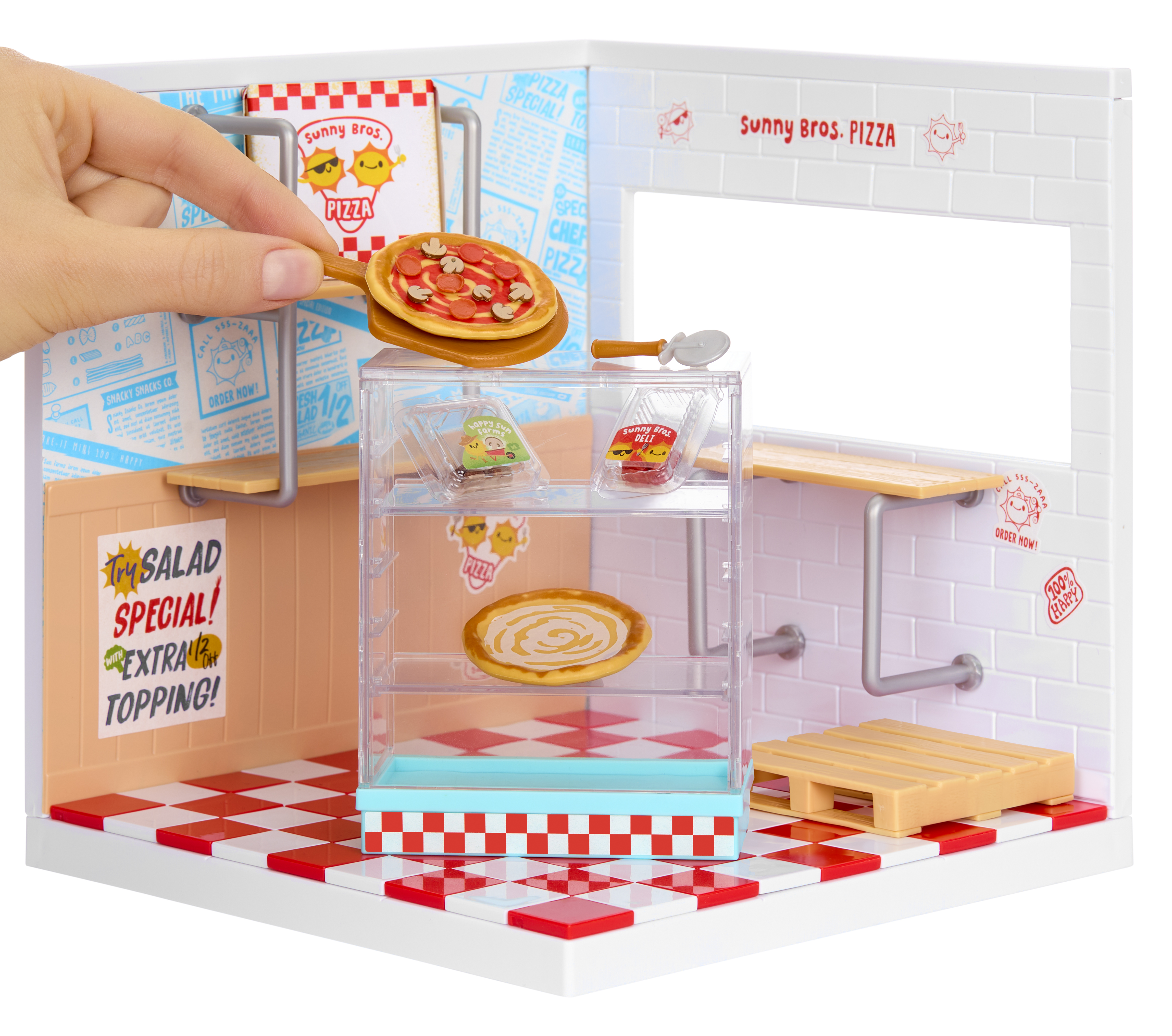 Una mano sostiene una pizza en miniatura con champiñones y pepperoni sobre un expositor de pizzería.
