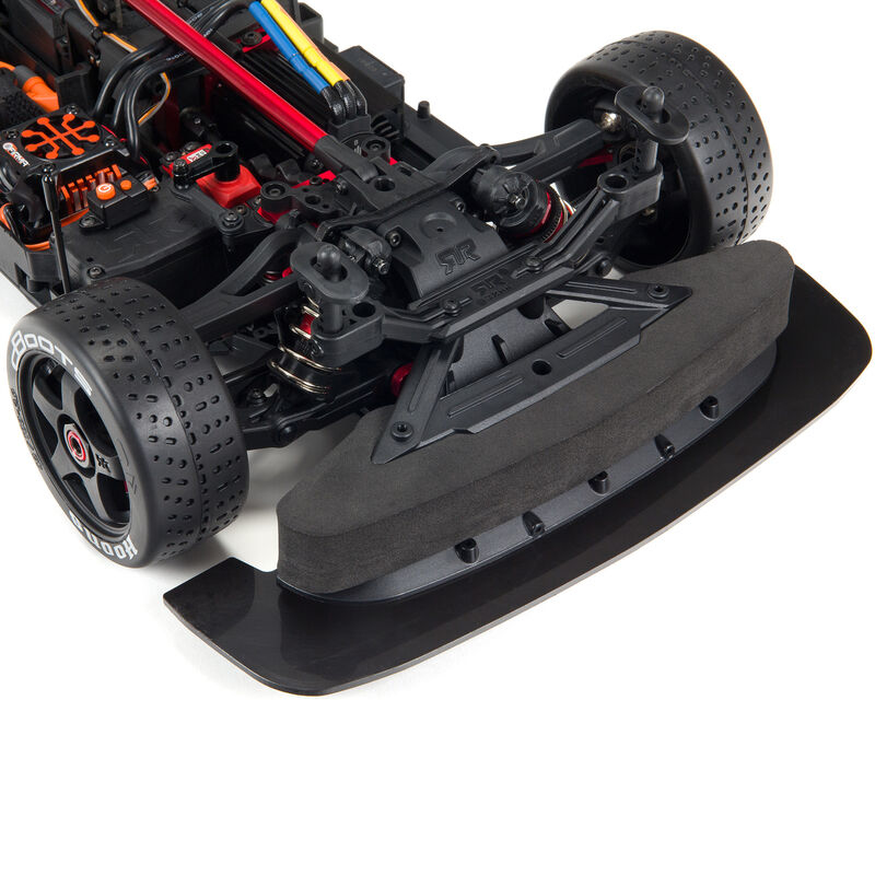 Primer plano del chasis de un coche RC. Divisor frontal negro con parachoques de espuma, suspensión y rueda.
