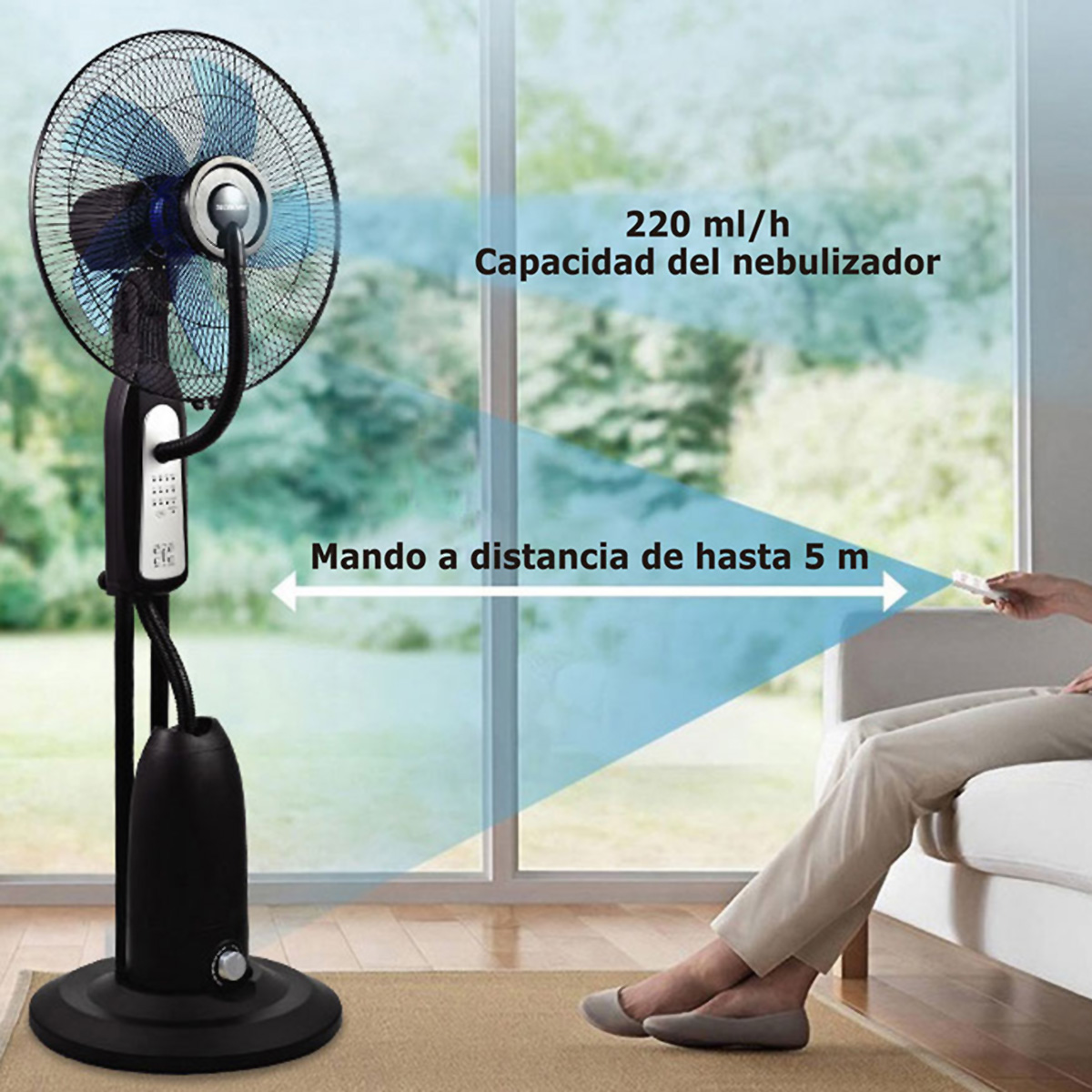 Un ventilador de pie negro con cabezal azul y panel de control. Las piernas de una persona son visibles en un sofá, operando un control remoto.