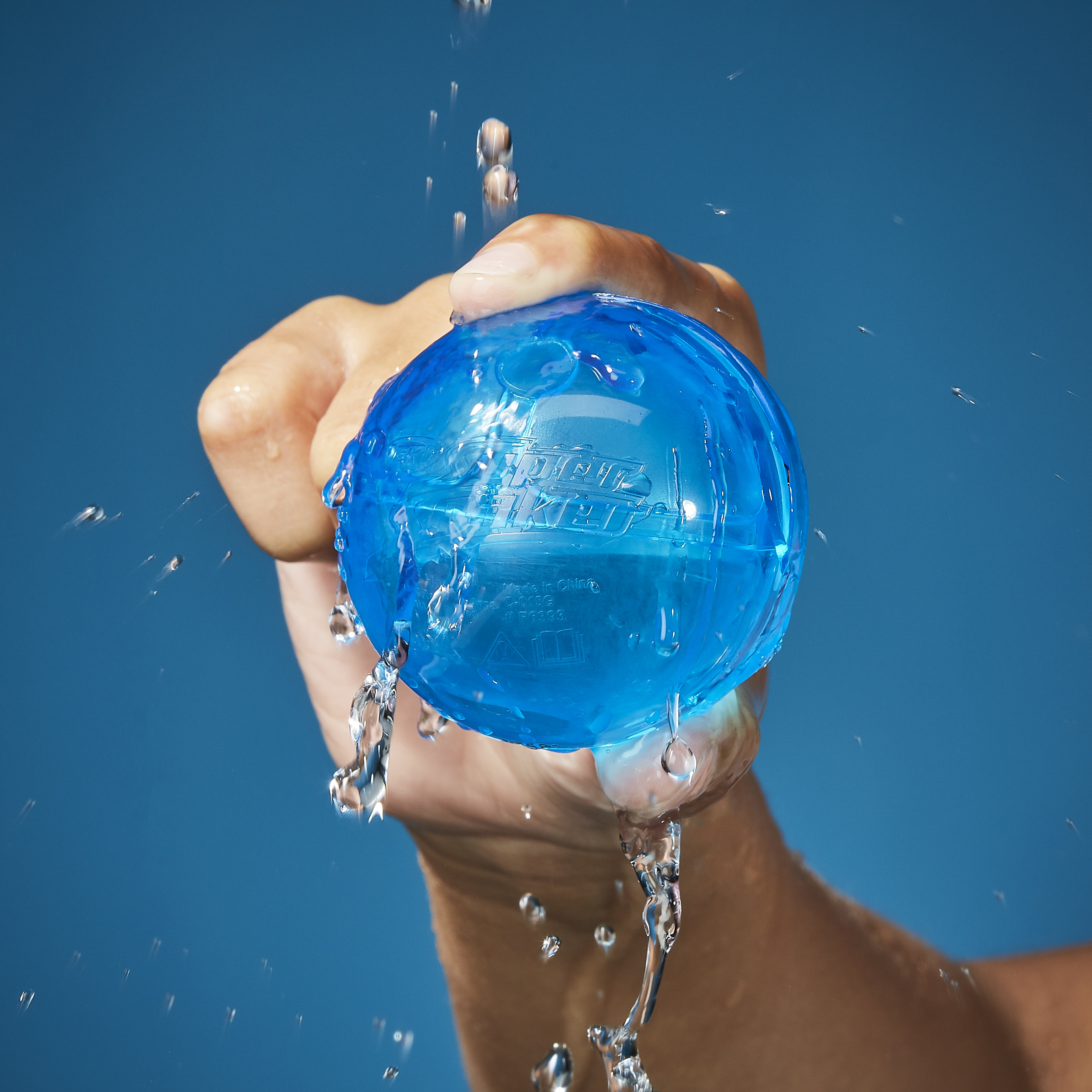 Blaue Kugel in Hand, Wasser tropft.