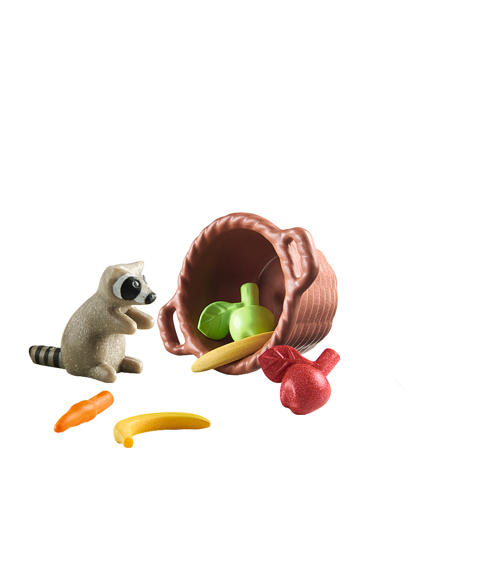 Ein Waschbär sitzt neben einem umgekippten Korb mit Früchten und Gemüse.