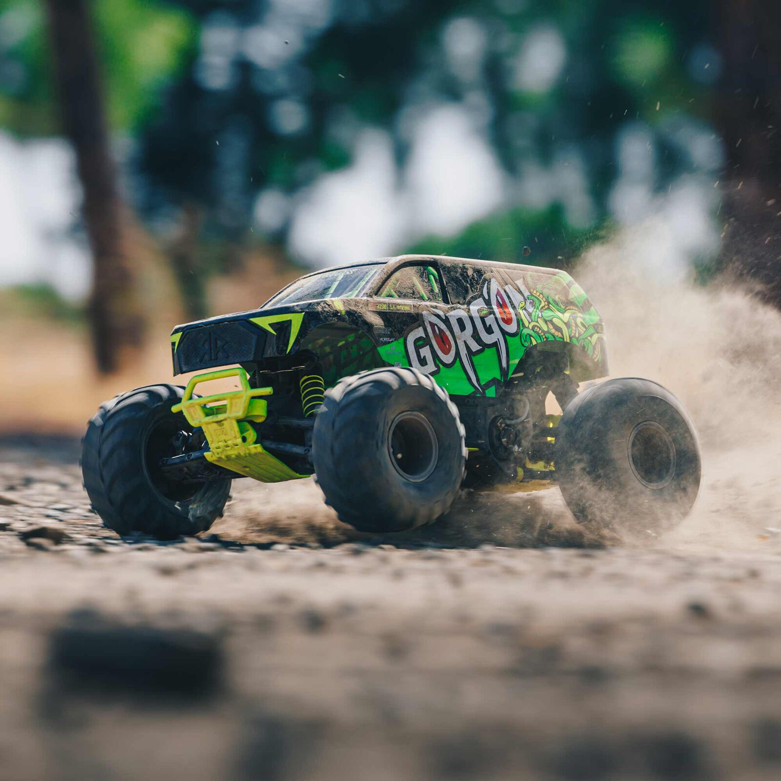 Un monster truck verde y negro avanza por terreno irregular levantando polvo.