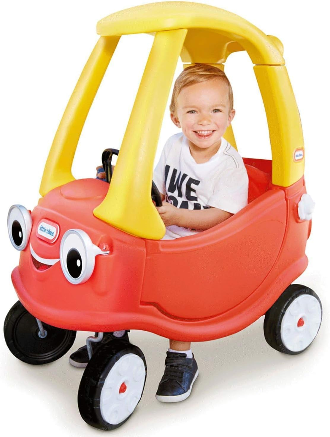 Un bambino sorridente siede in una macchinina rossa con tetto giallo.