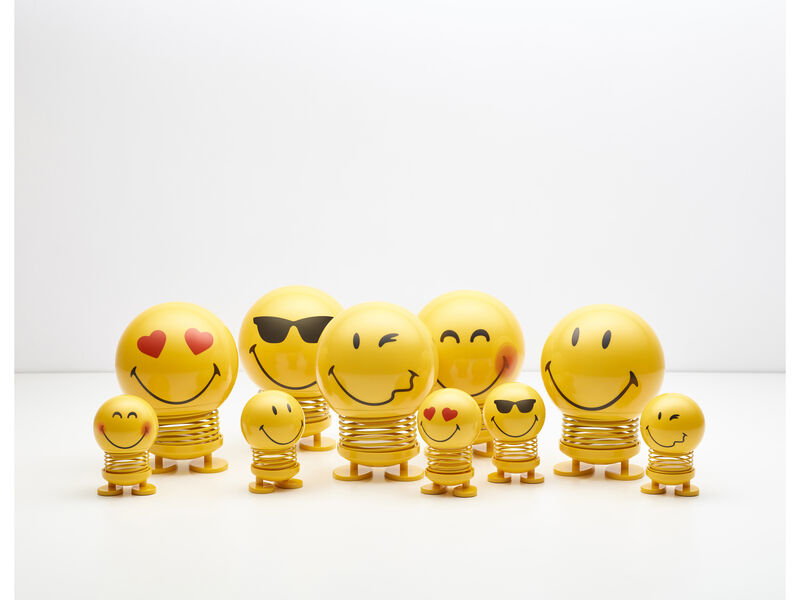 Un gruppo di figure a molla smiley gialli di varie dimensioni su sfondo bianco.