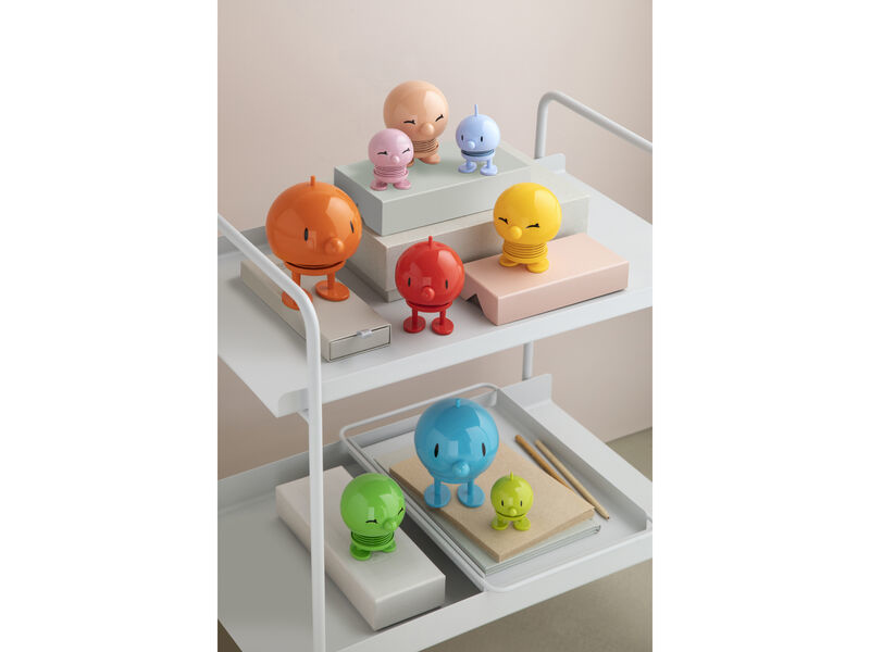 Figure colorate su uno scaffale bianco. Ripiano superiore: figure arancioni, rosse, gialle, rosa, blu, beige.