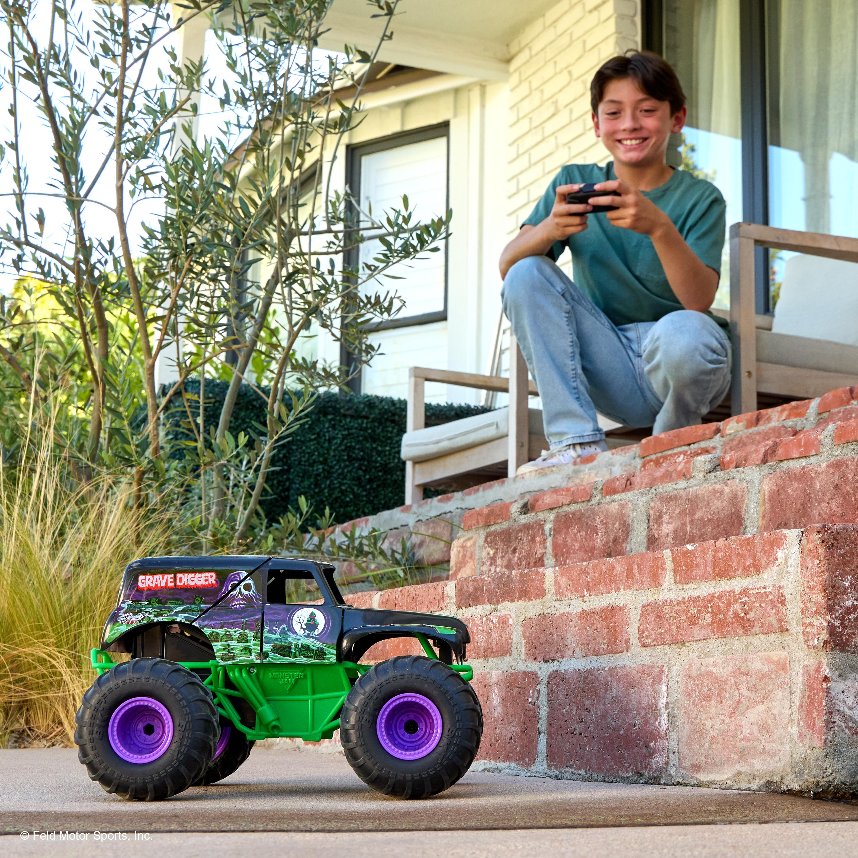 Ein Junge spielt mit einem ferngesteuerten Monstertruck auf einer Steintreppe vor einem Haus.