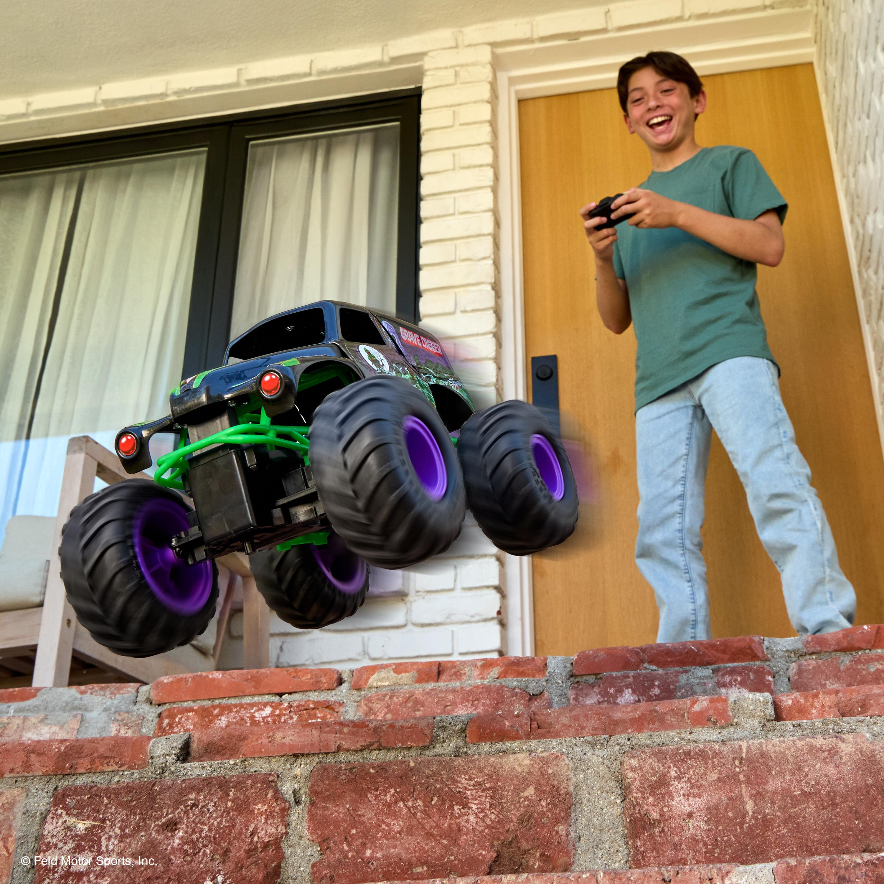 Ein Junge spielt mit einem ferngesteuerten Monster-Truck, der in der Luft springt.