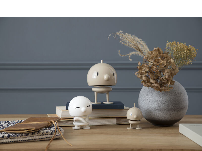 Tre figure decorative su un tavolo di legno con libri, stoffa e fiori secchi in un vaso.
