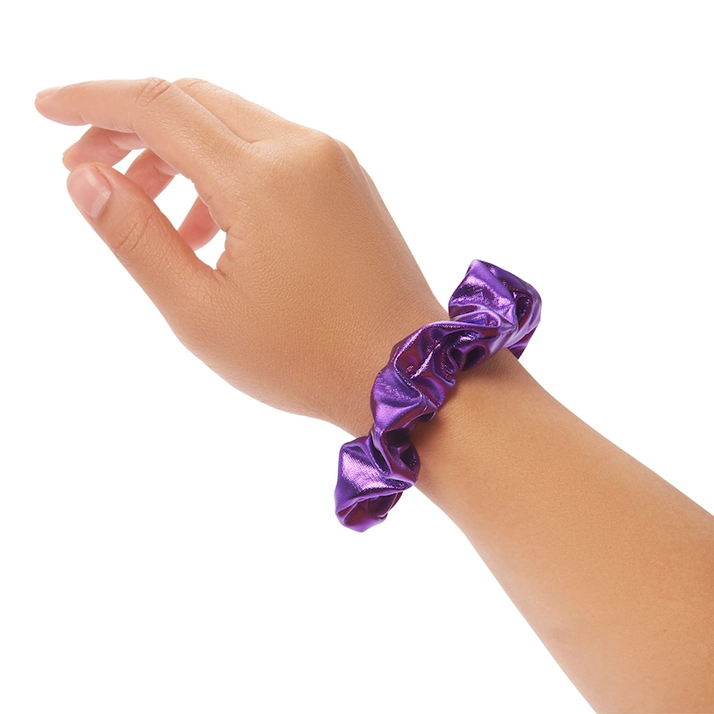 Il braccio di una persona con uno scrunchie viola lucido al polso, su uno sfondo bianco semplice.