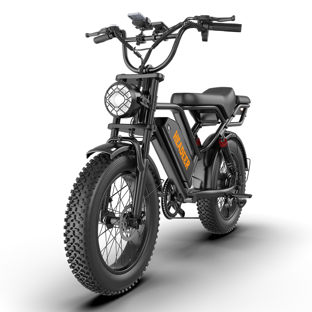 Bicicleta eléctrica negra con neumáticos anchos, faro redondo y letras naranjas.