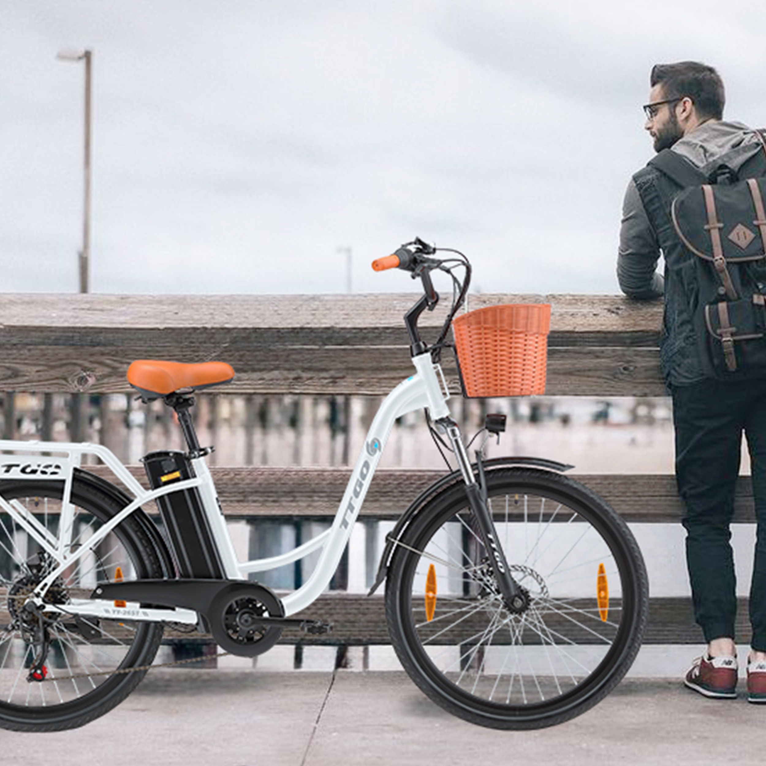 Ein Mann mit Rucksack steht neben einem weißen Elektrofahrrad auf einer Holzpromenade und blickt auf das Wasser.