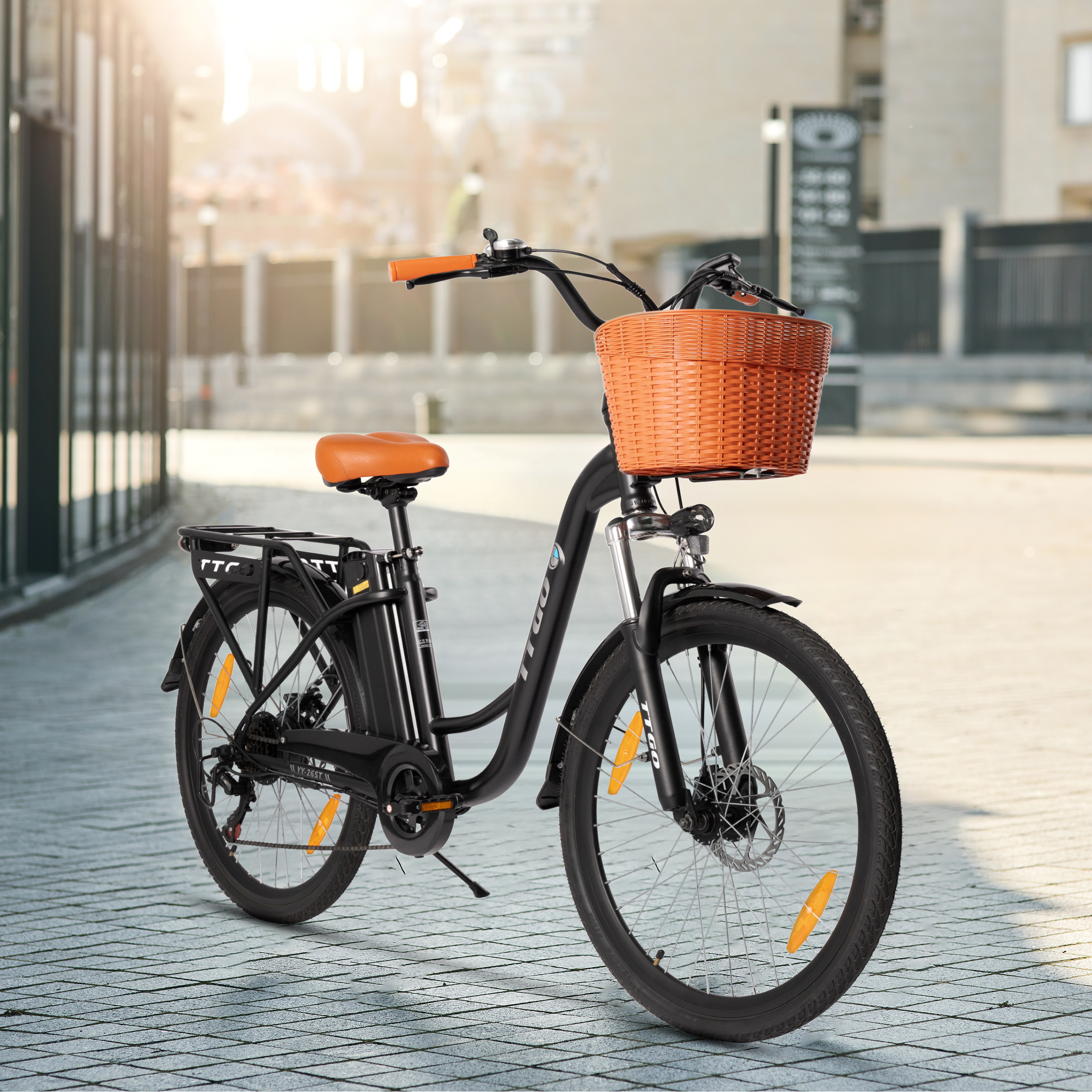 Ein schwarzes E-Bike mit orangefarbenem Korb und Sattel steht auf einem Gehweg.