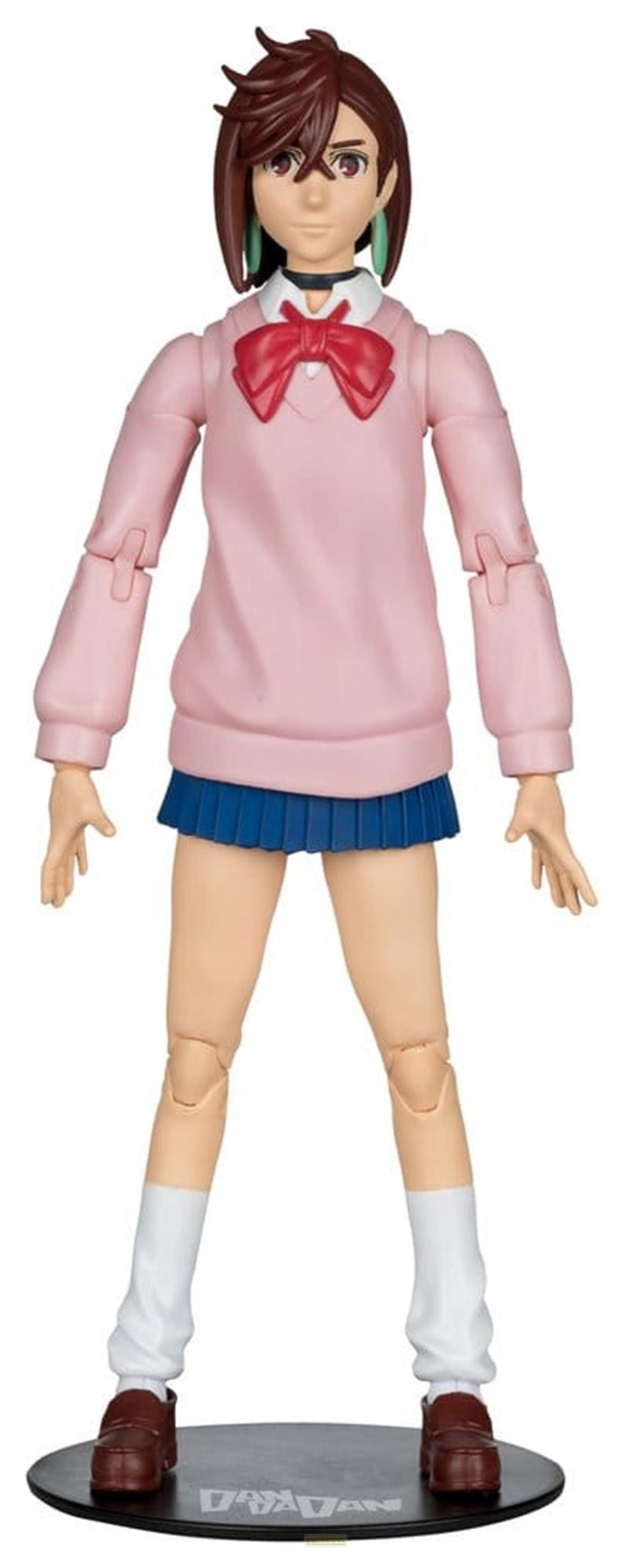 Eine Figur in einem rosafarbenen Pullover, blauem Rock, weißen Socken und braunen Schuhen.