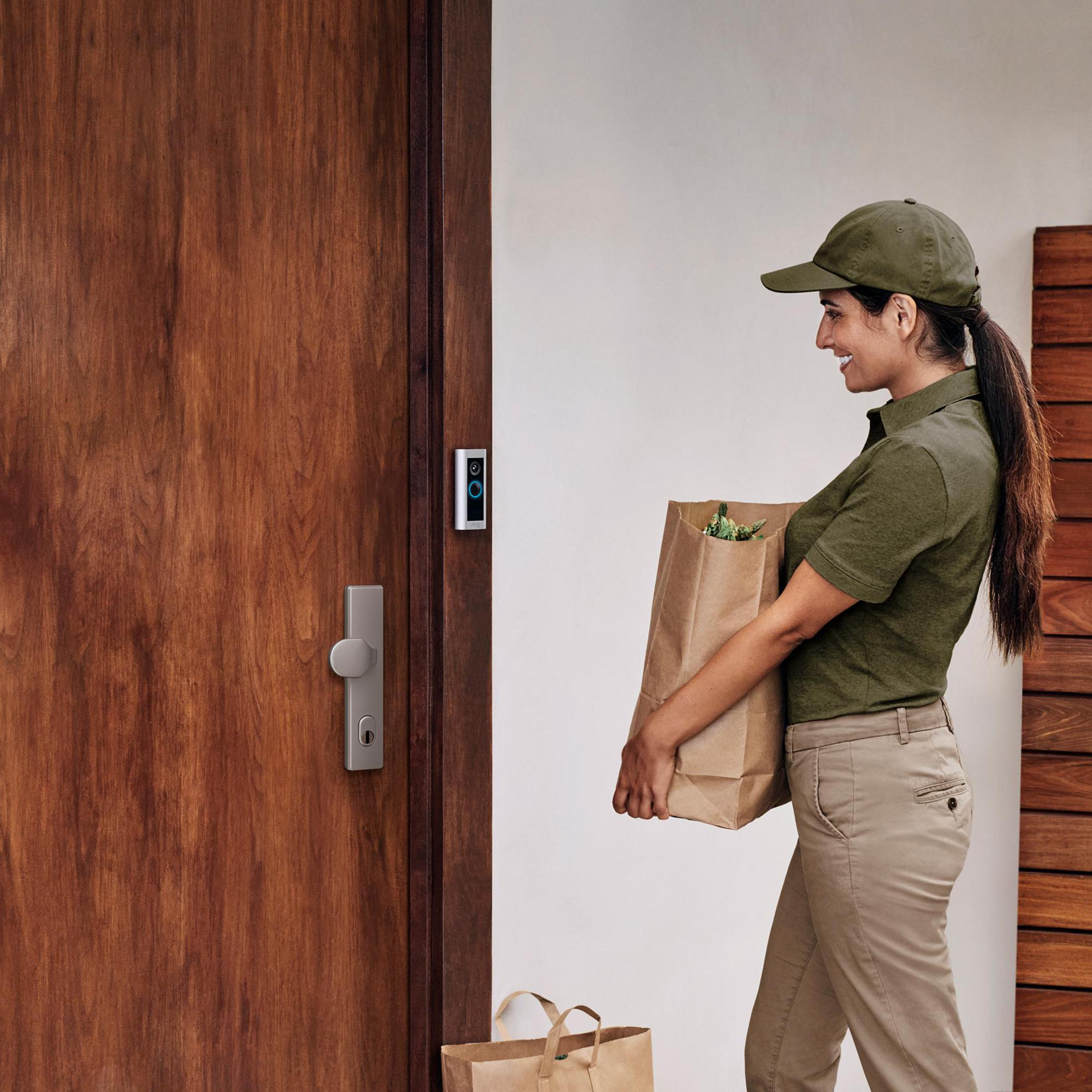 Una donna con camicia e cappellino verdi porta una borsa di carta della spesa.