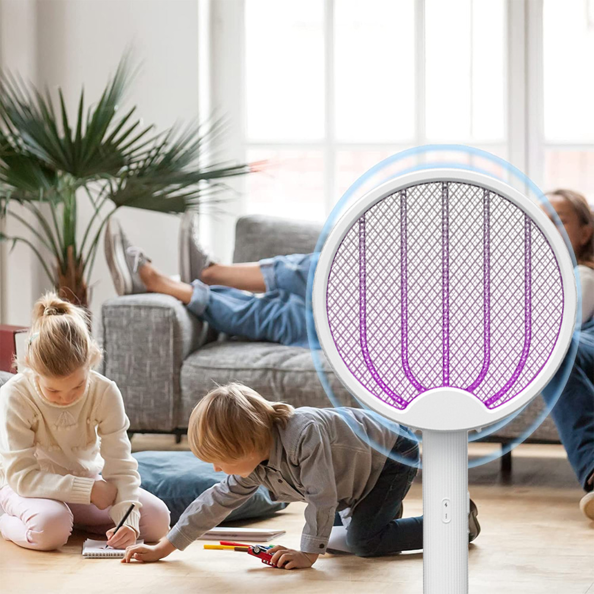 Kinder malen und spielen, während eine Person auf dem Sofa liegt. Ein elektrischer Fliegenfänger ist im Vordergrund.