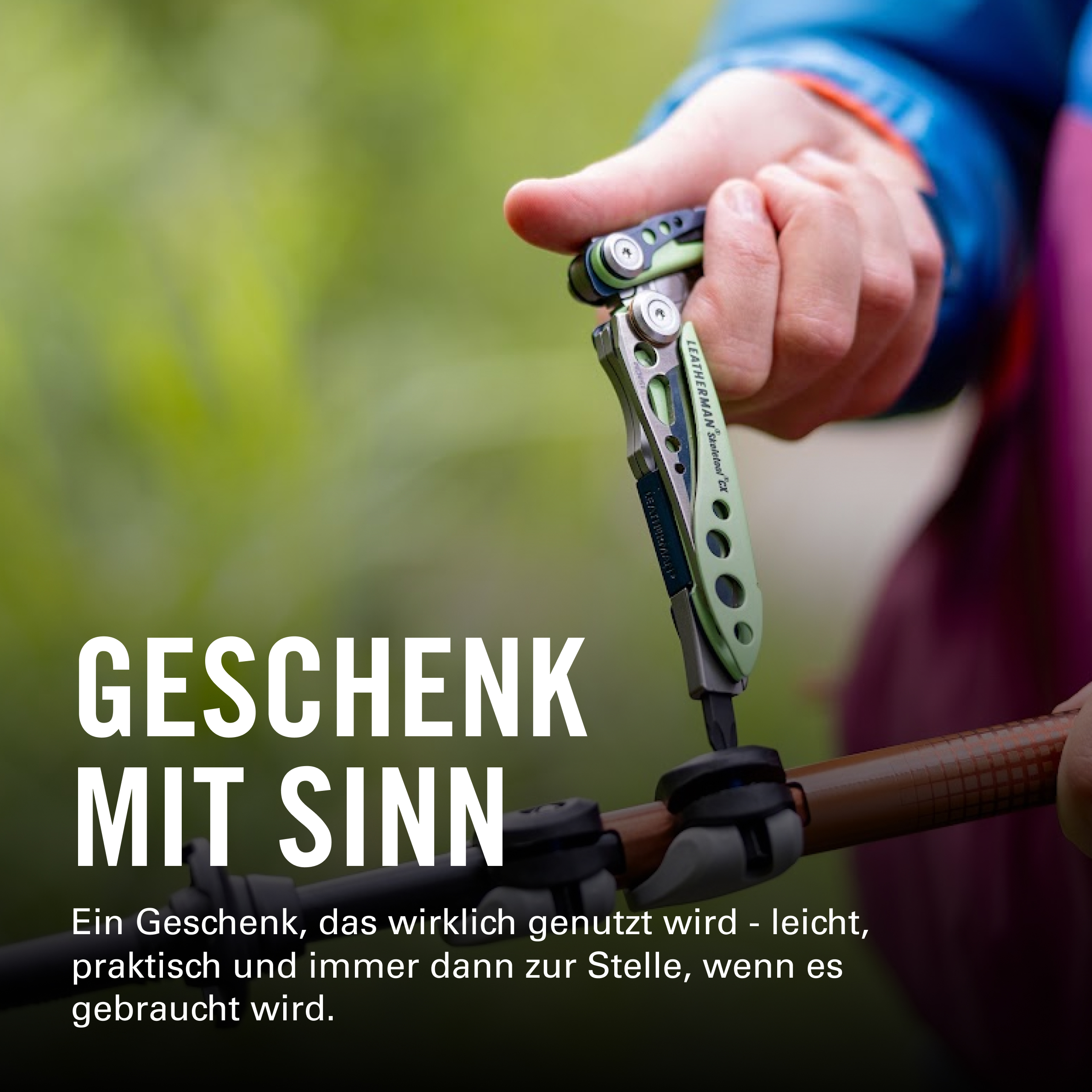 Eine Person in einer blauen Jacke hält ein grünes und silbernes Leatherman Skeletool CX und befestigt es an einem braunen Wanderstock.