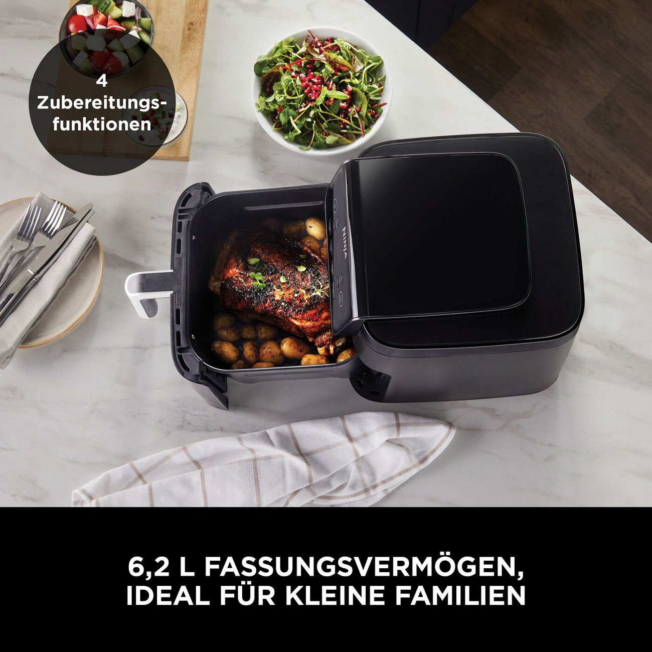 Ein schwarzer Ninja Airfryer mit Braten und Kartoffeln, daneben Salat. 4 Zubereitungsfunktionen.