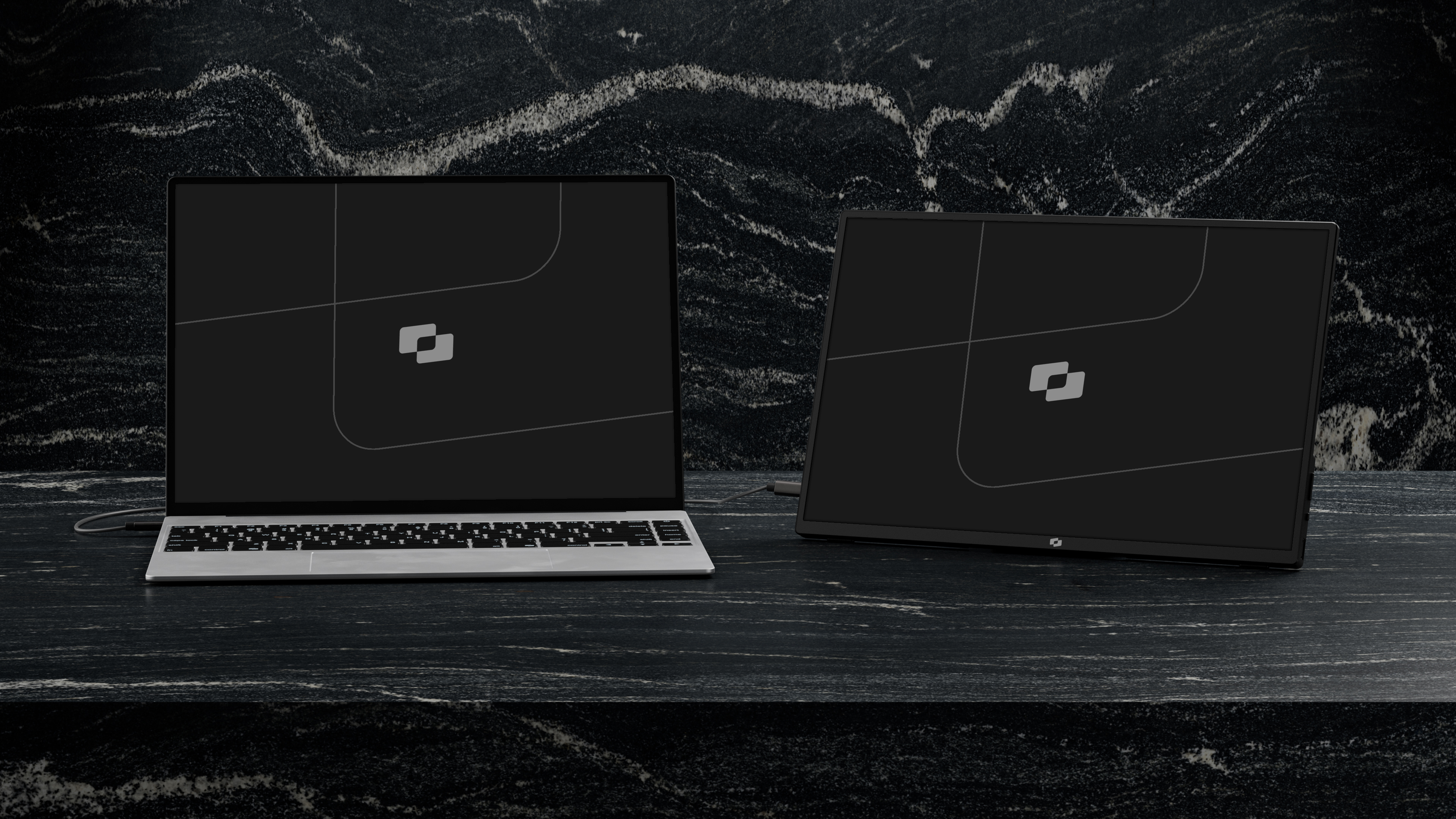 Een laptop en een monitor staan naast elkaar op een donker marmeren aanrecht.