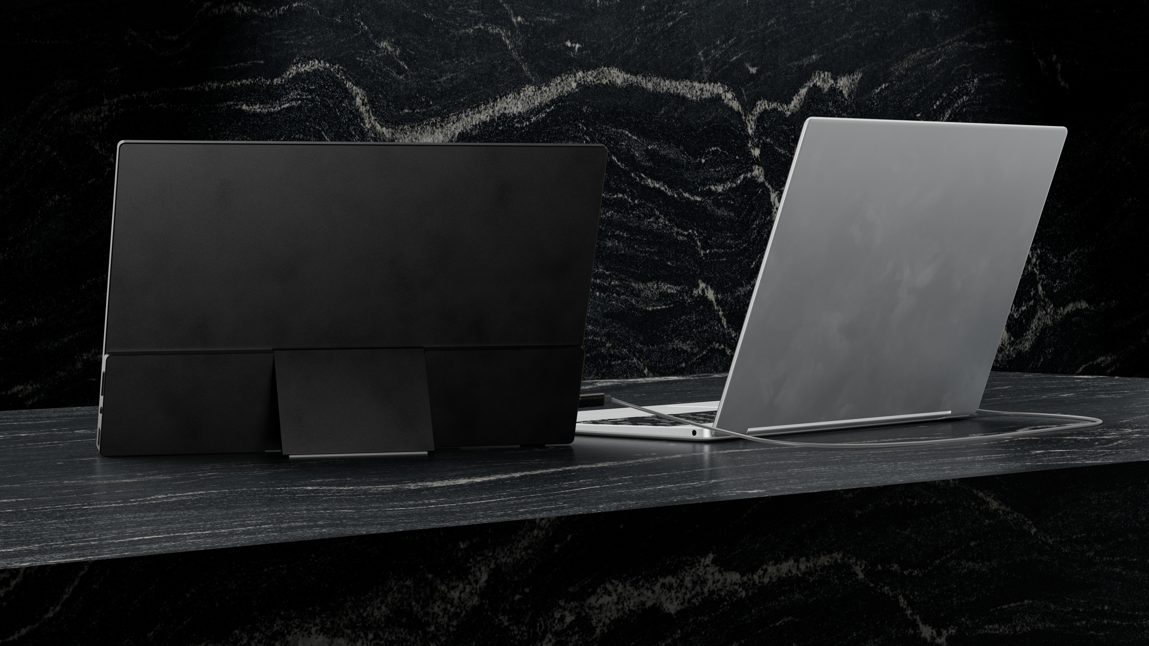 Een zwarte laptop en een zilveren laptop staan naast elkaar op een donker marmeren oppervlak.