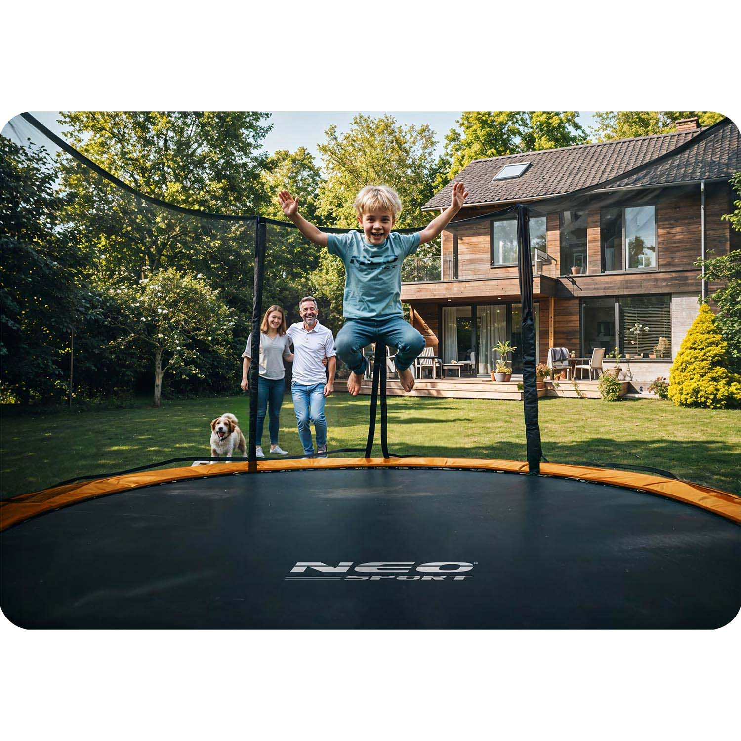 Niño salta en trampolín, padres y perro observan, casa al fondo.