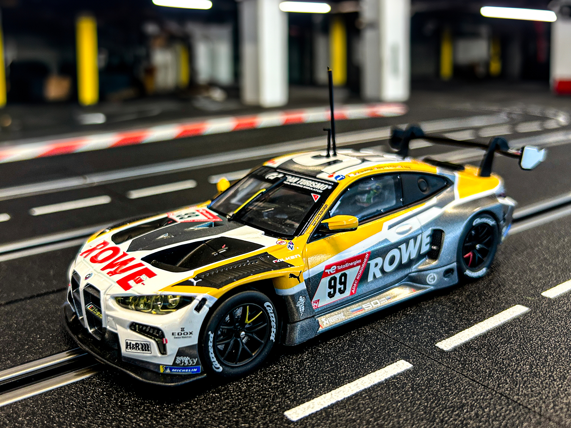 Ein gelb-silberner Rennwagen mit der Nummer 99 auf einer Slotcar-Bahn.