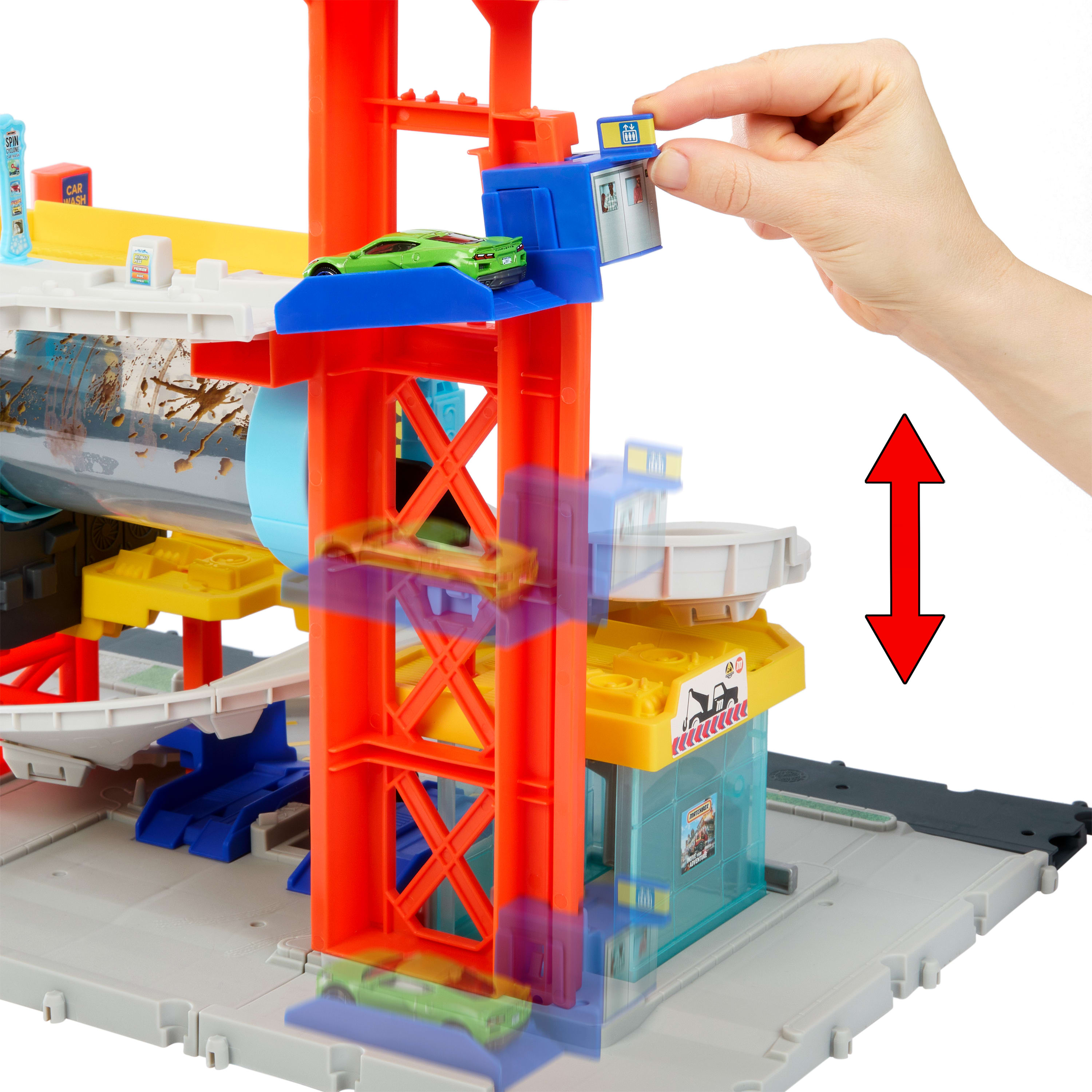 Ein Spielzeugauto-Garage mit einer Hand, die einen Aufzug platziert. Enthält Autos und eine Autowaschanlage.