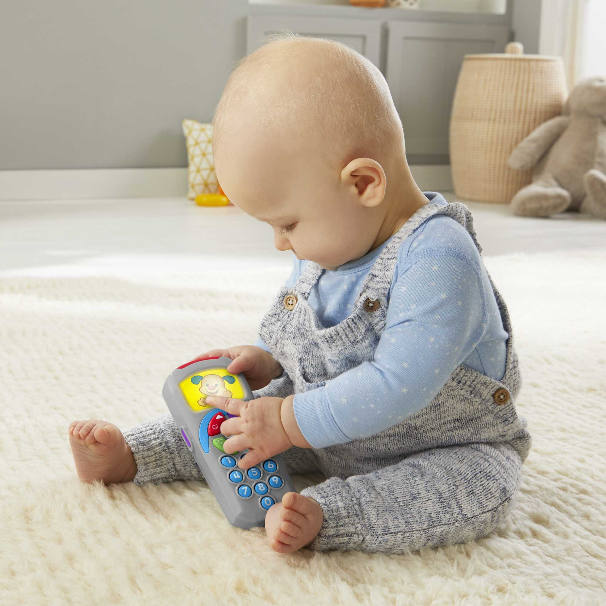 Ein Baby spielt mit einem Spielzeughandy auf einem Teppich.
