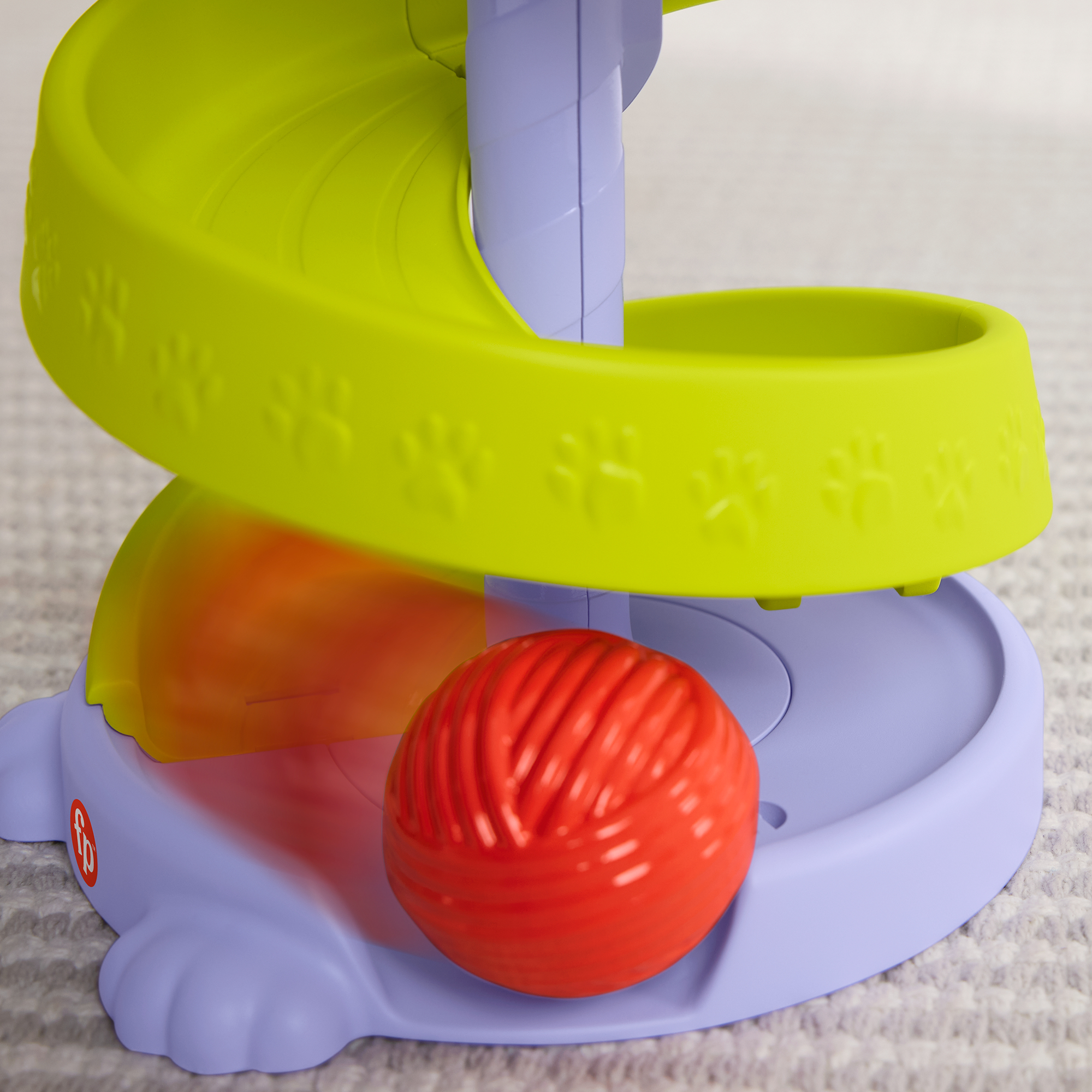 Ein roter Ball auf einer lilafarbenen Basis mit einer grünen Rampe.