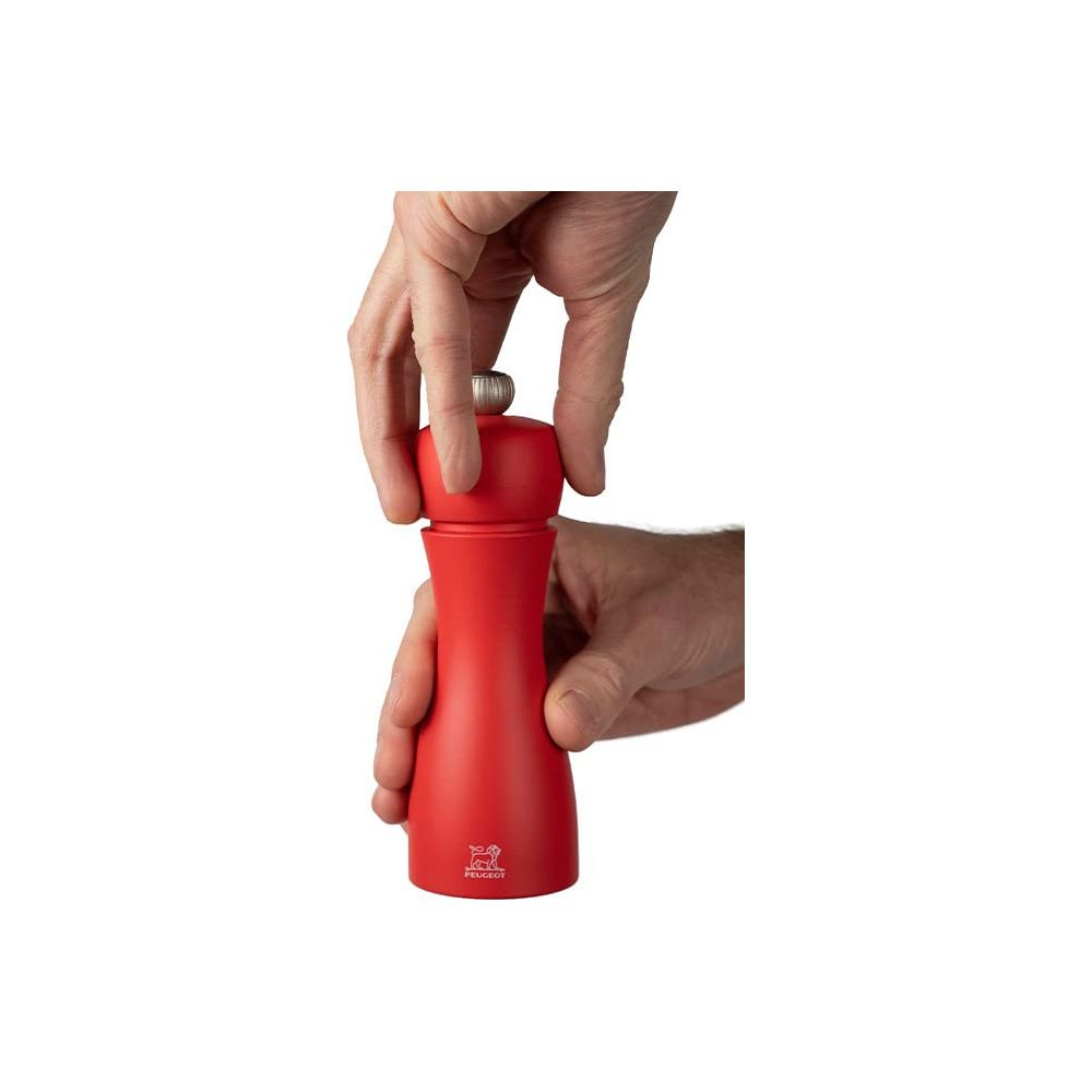 Rote Peugeot Pfeffermühle wird von Händen gehalten.