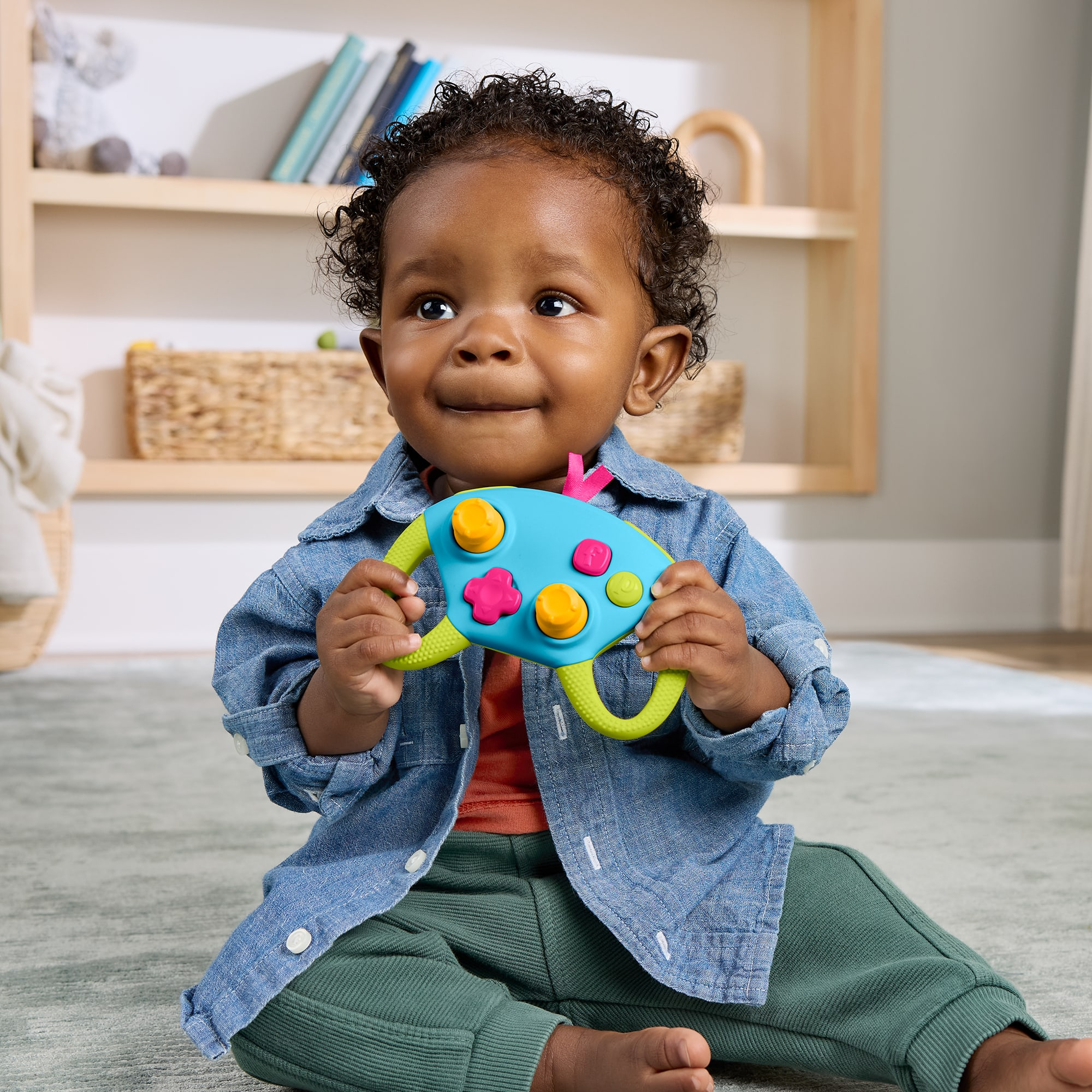 Ein Baby sitzt auf dem Boden und hält ein buntes Spielzeug.
