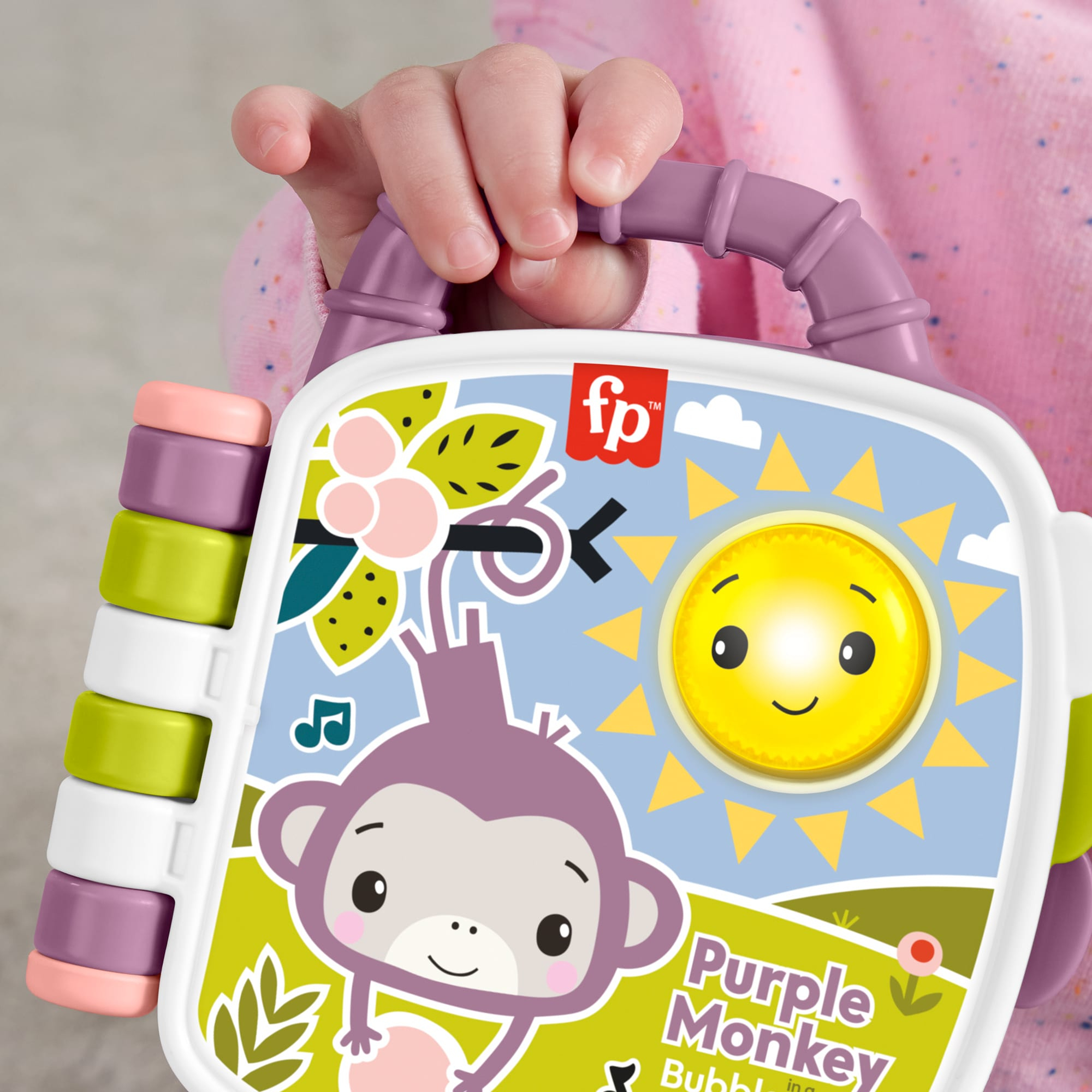 Baby hält ein lila Spielzeug mit Affenmotiv, Sonne und Tasten.