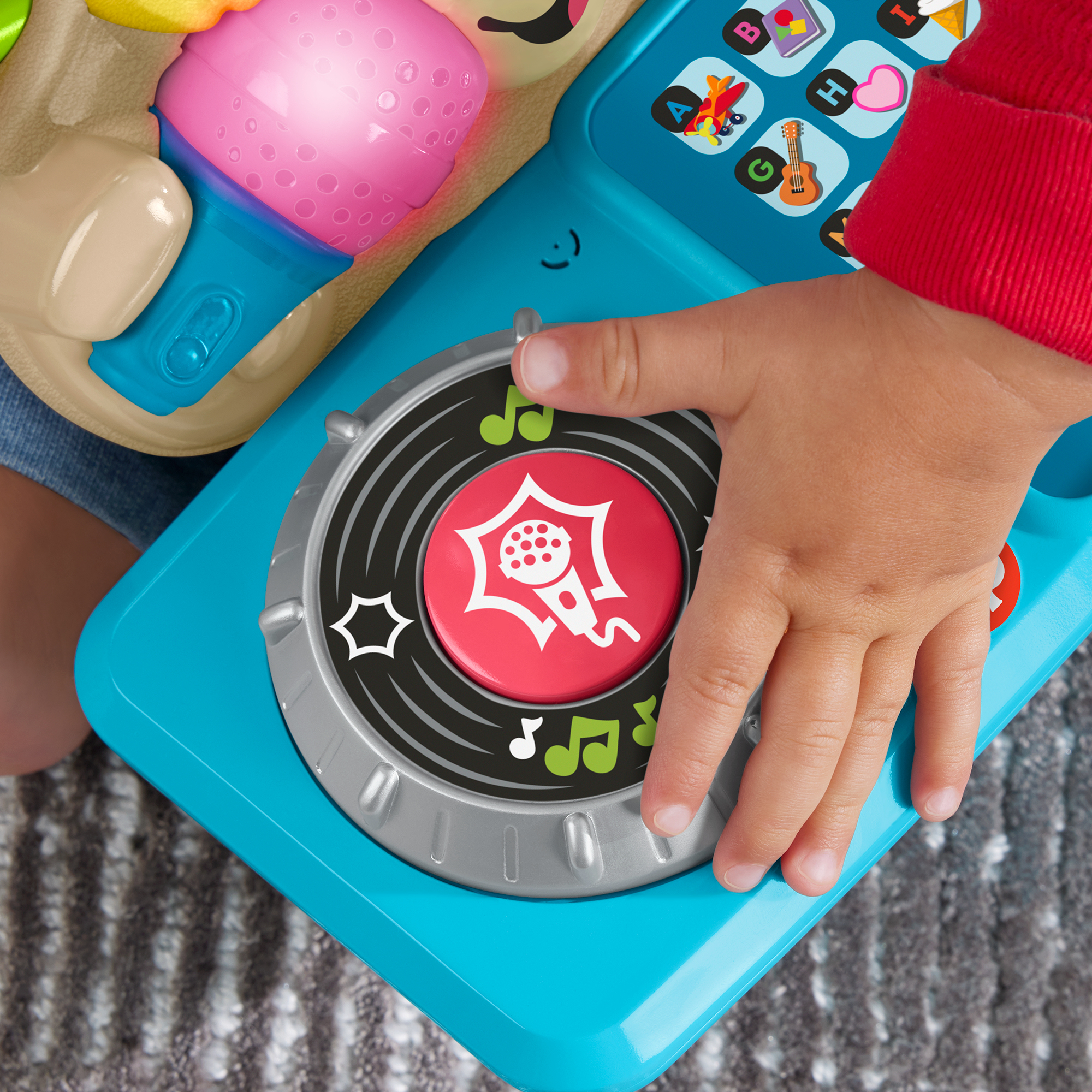 Ein Kind drückt auf einen Spielzeug-DJ-Pult mit Mikrofon-Symbol.