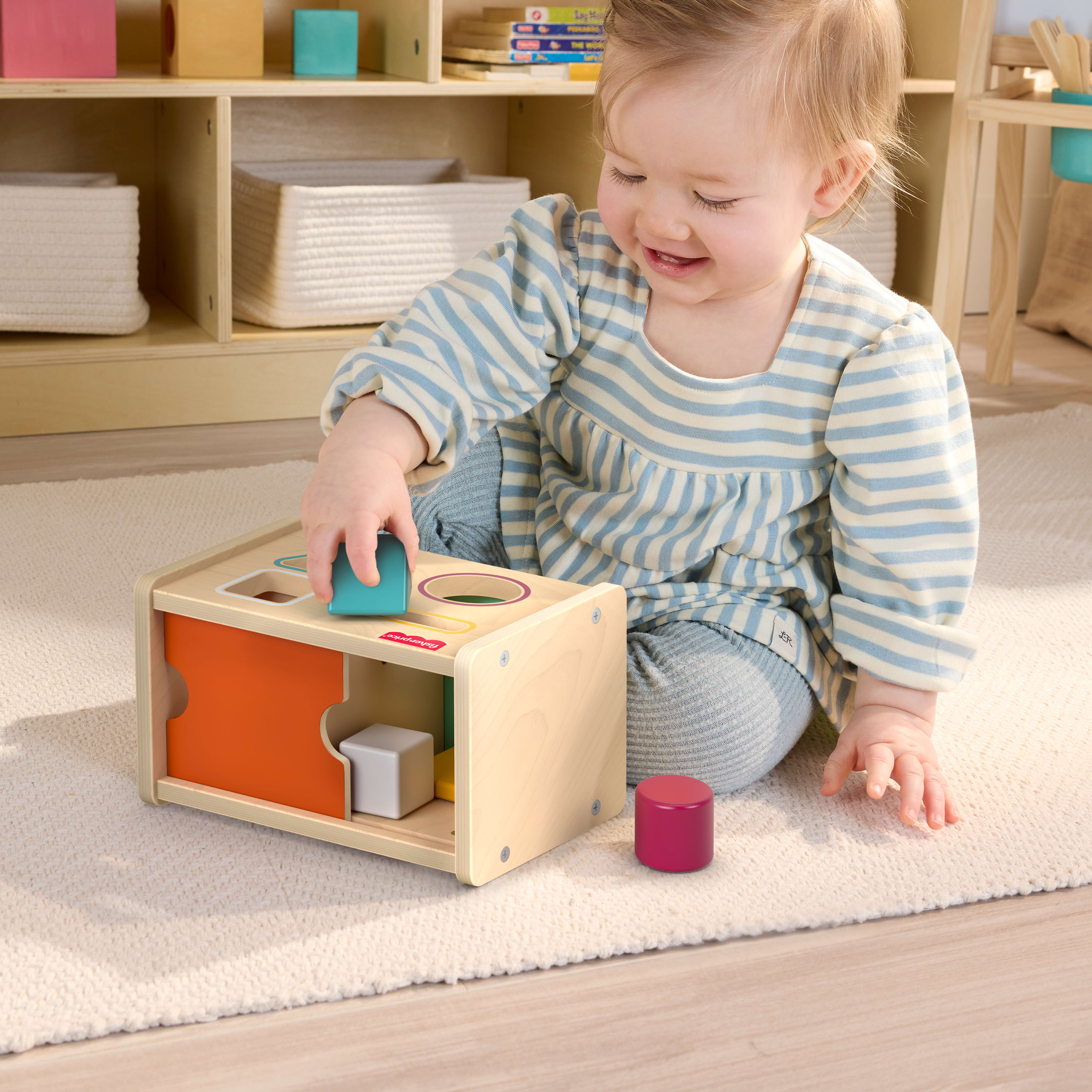 Ein Baby spielt mit einem Holzsortierspielzeug auf einem Teppich.