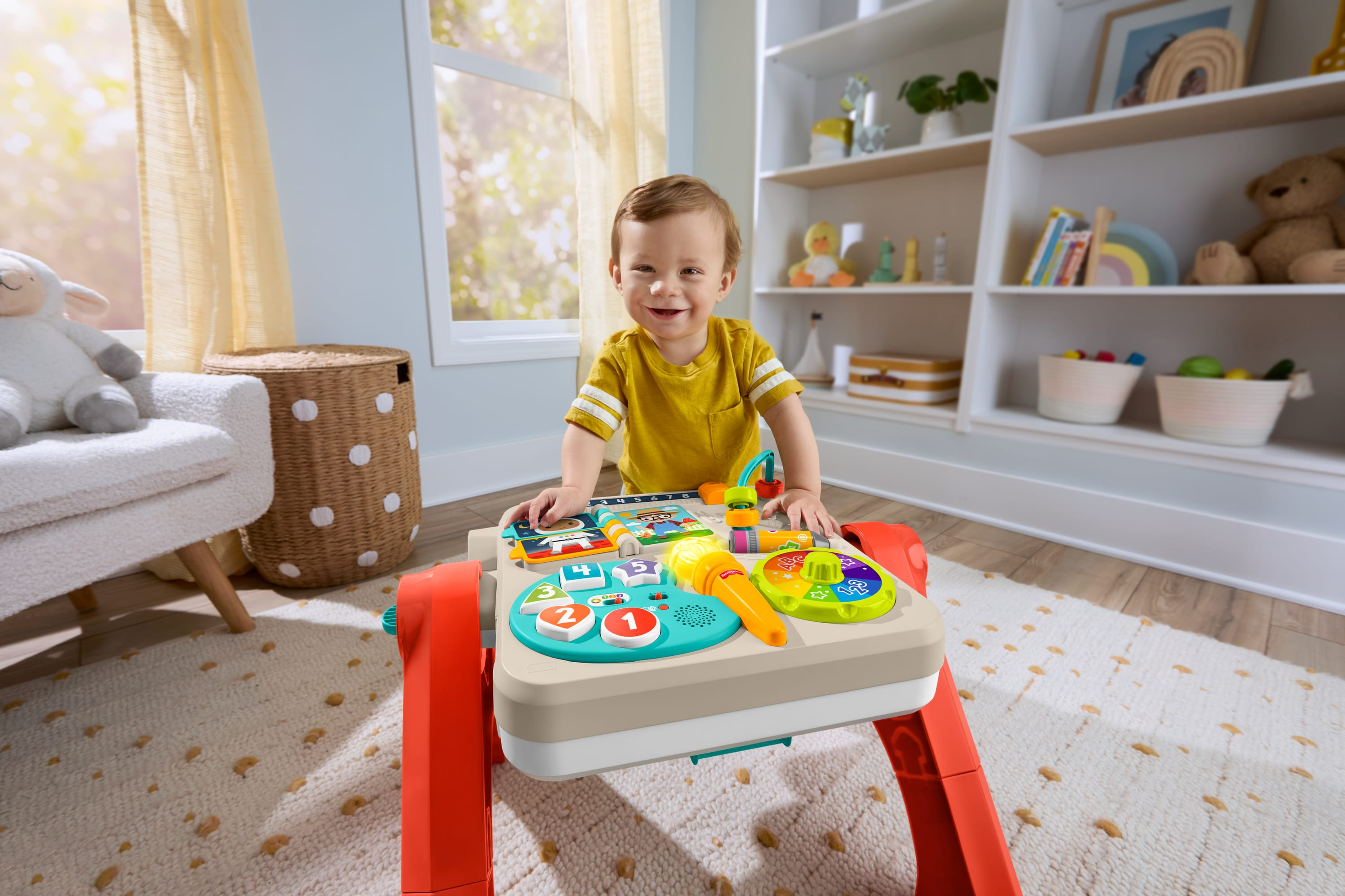 Ein Kleinkind lacht vor einem Spieltisch mit Lichtern und Knöpfen.