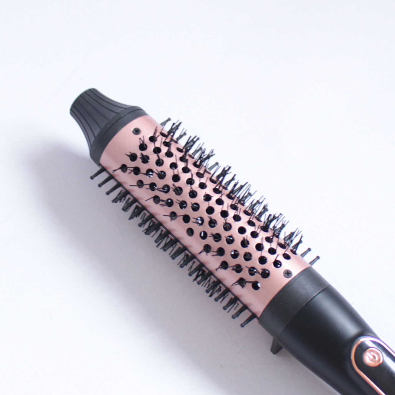Eine rosegold-schwarze Heißbürste mit Borsten und Lüftungslöchern, schräg auf weißem Hintergrund.