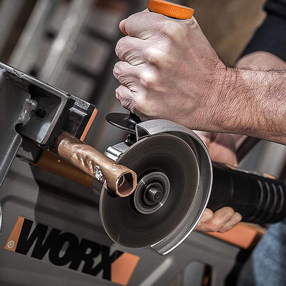 Adam açılı taşlama makinesiyle bakır boru kesiyor, arkada WORX logosu.