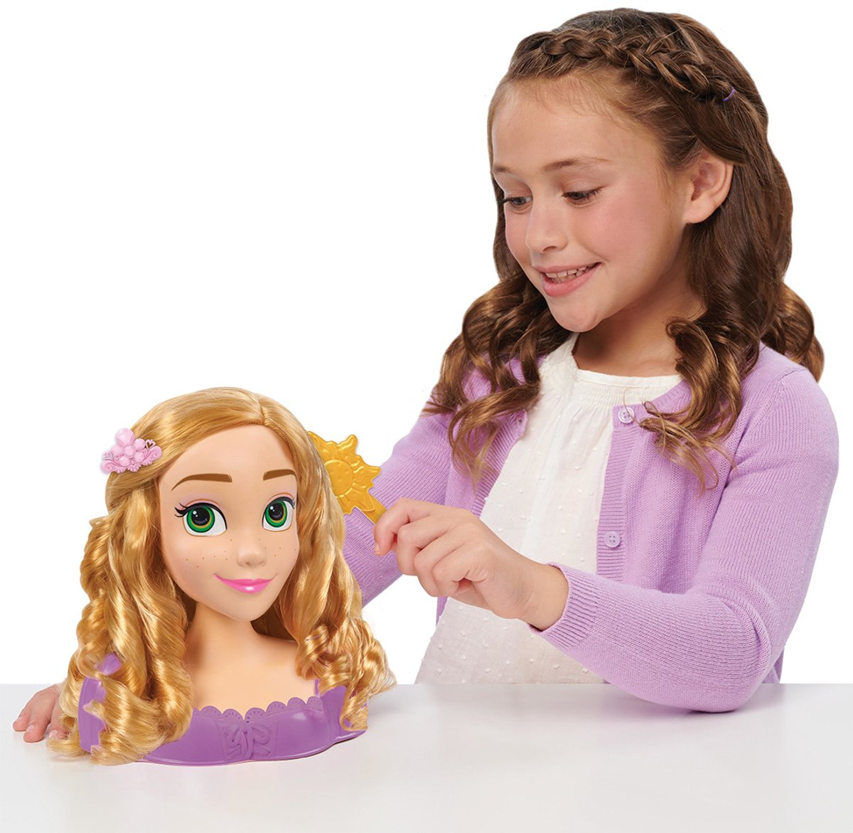 Ein Mädchen kämmt die Haare einer Rapunzel-Puppe mit einer goldenen Sonnenspitzkamm.