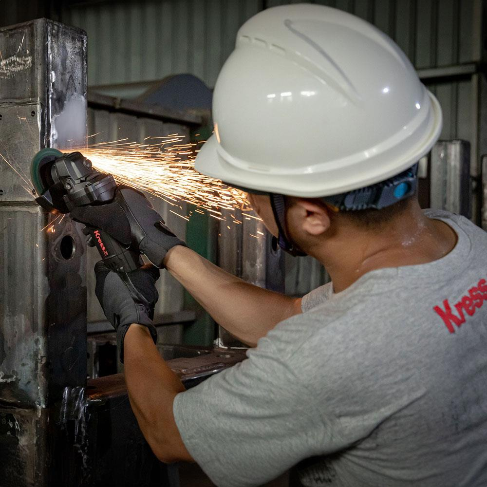 Kasklı adam metal zımparalıyor, kıvılcımlar uçuşuyor.