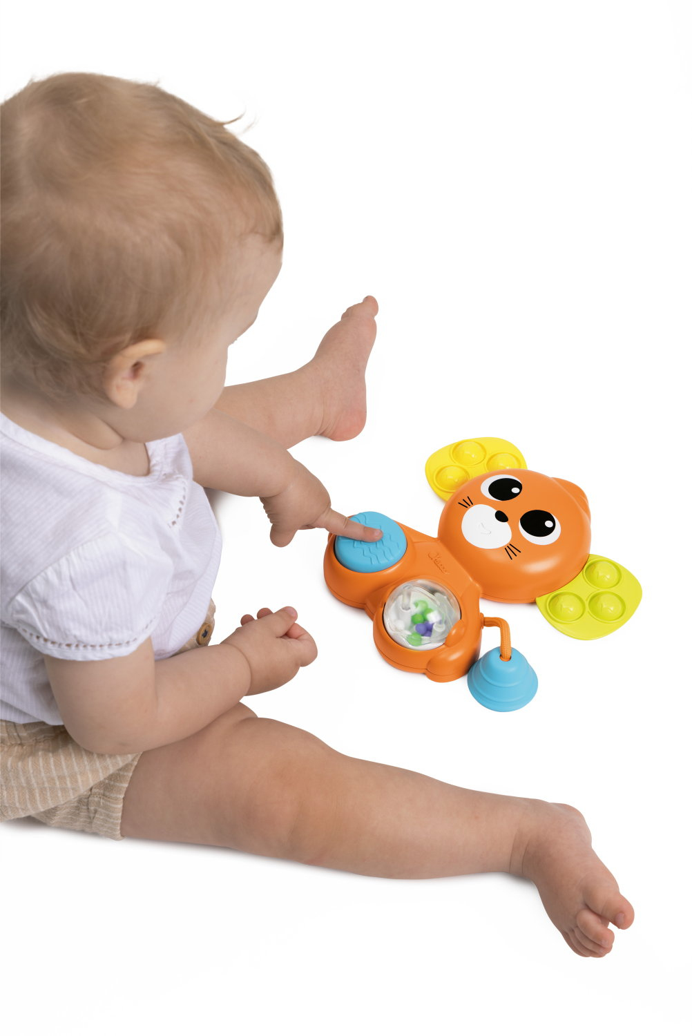 Ein Baby spielt mit einem bunten Spielzeug in Form eines Bären auf weißem Hintergrund.