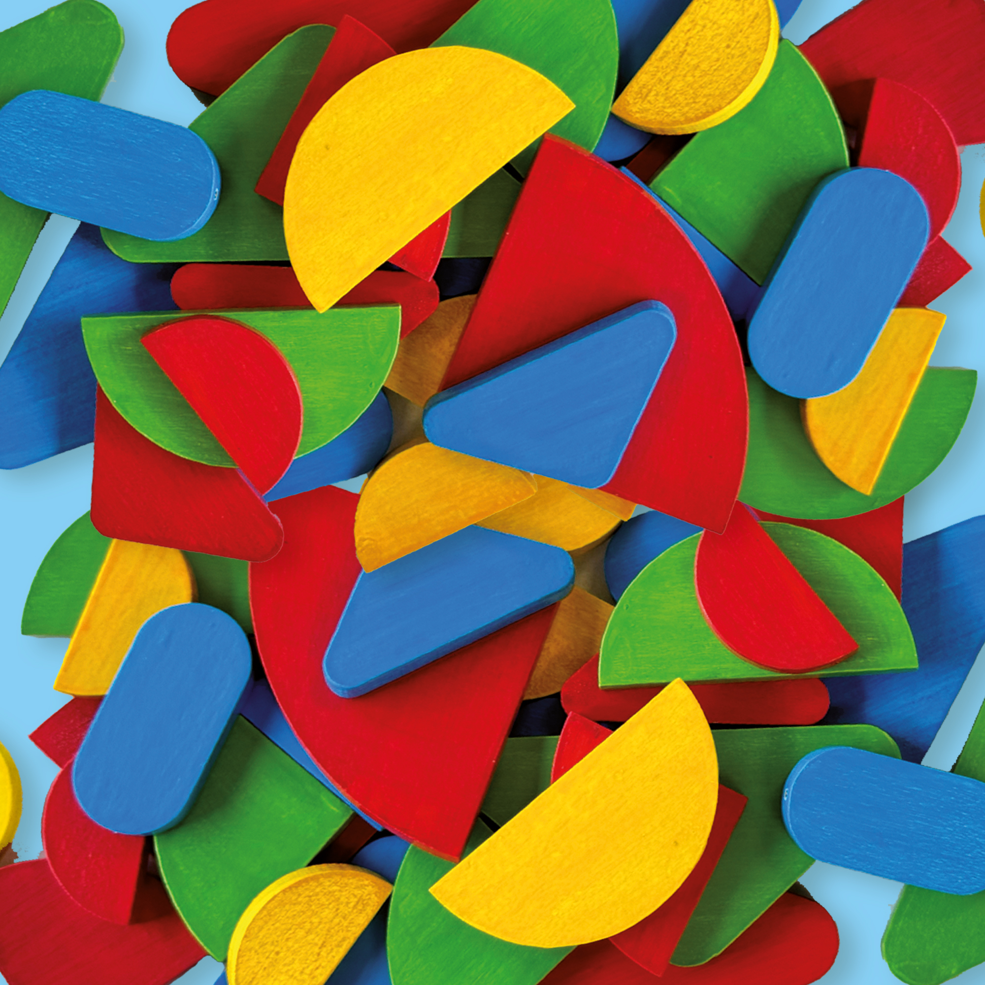 Eine Nahaufnahme zeigt eine lebendige Anordnung von bunten geometrischen Holzformen, die auf einer hellblauen Oberfläche verstreut sind.