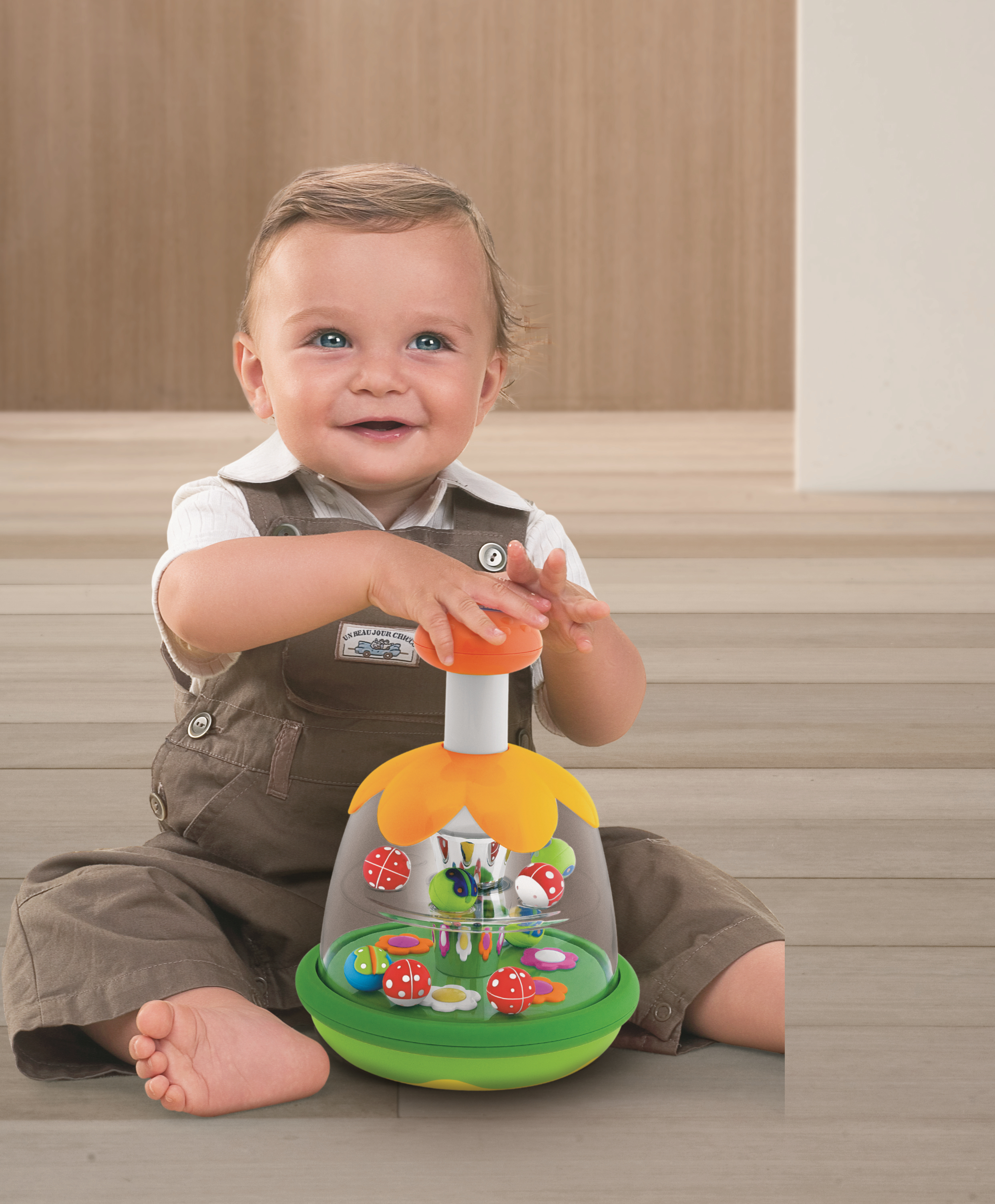 Ein Baby sitzt auf dem Boden und spielt mit einem bunten Spielzeug mit Kugeln.