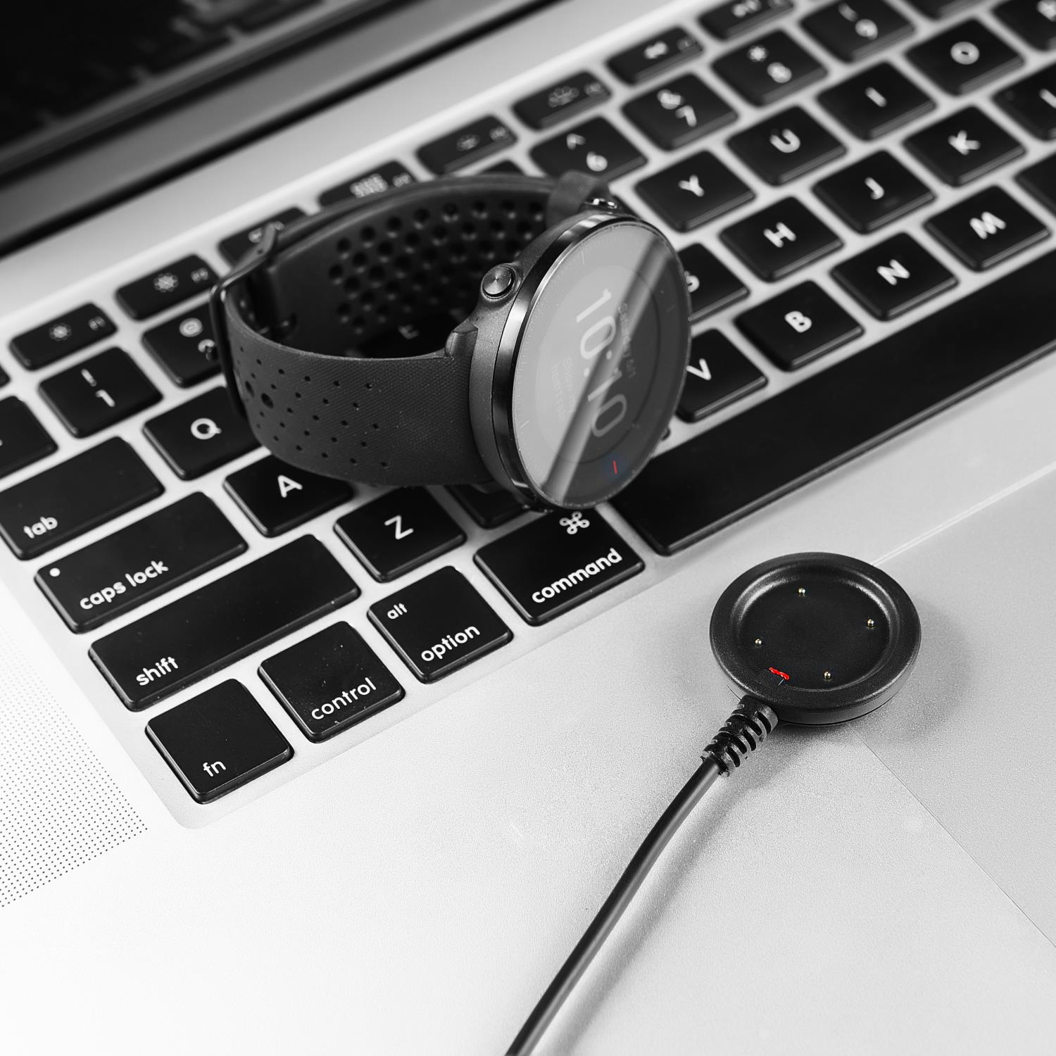 Eine Smartwatch und ihr Ladegerät liegen auf einer Laptop-Tastatur.