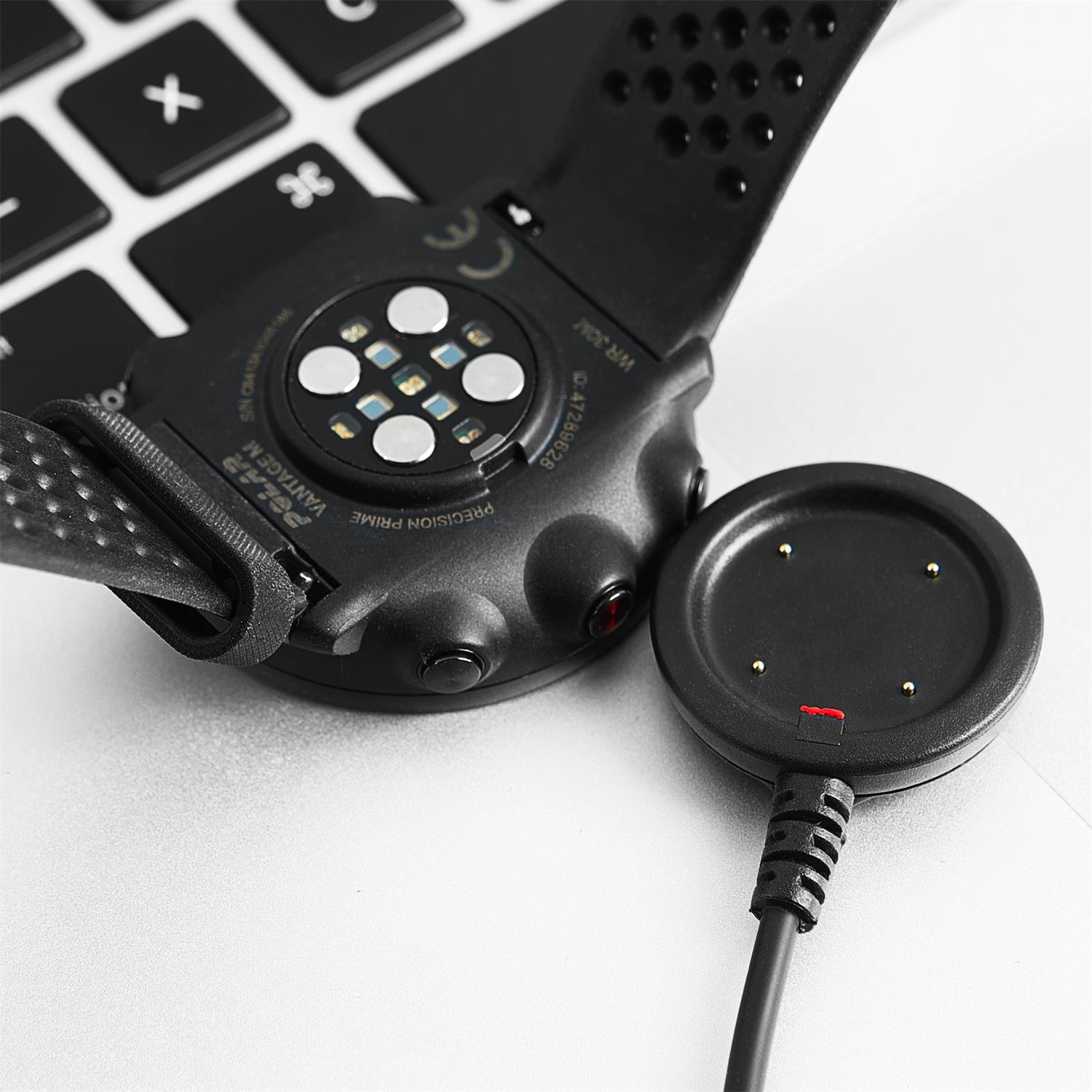 Schwarze Smartwatch mit Ladekabel auf Tastatur