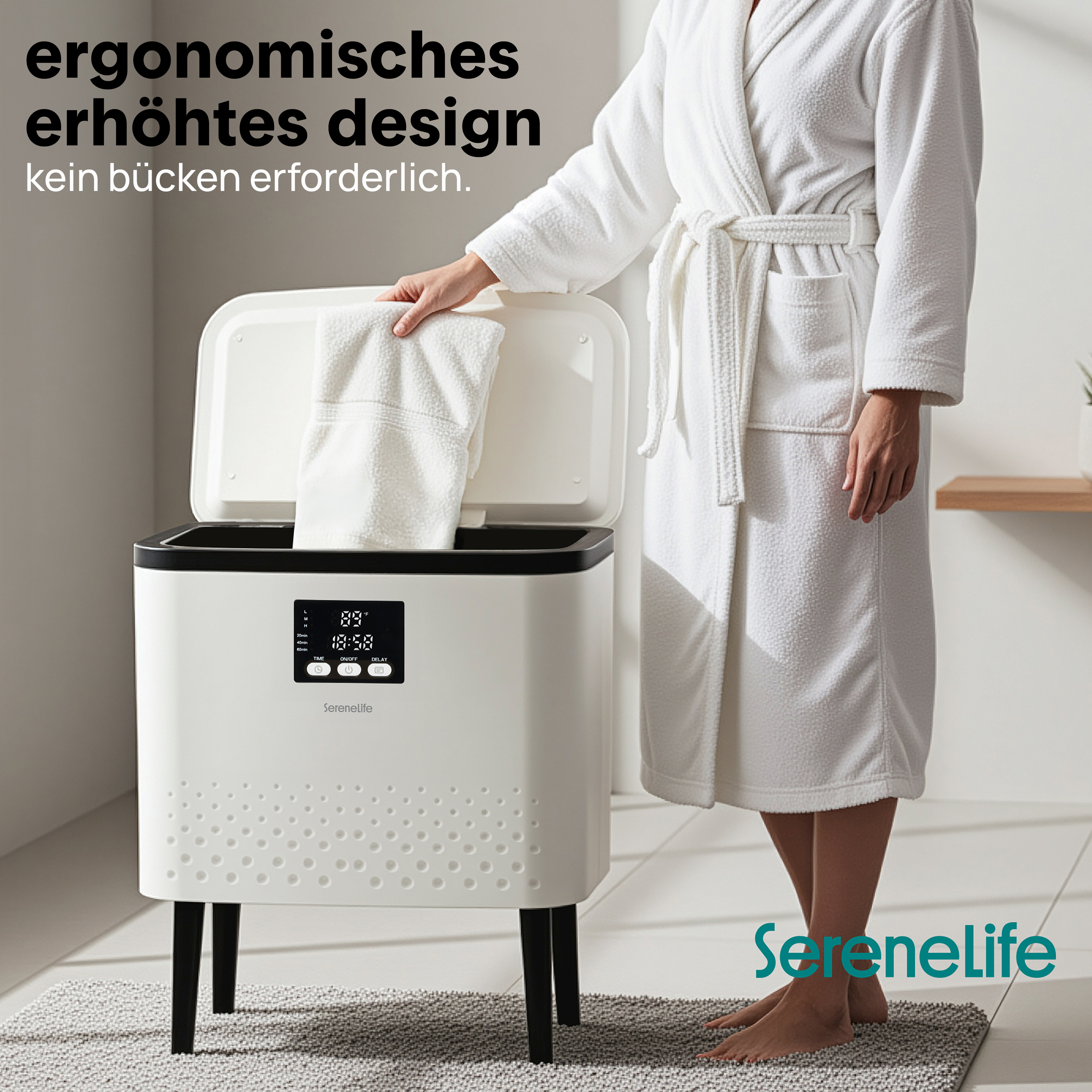 Eine Person im Bademantel hebt ein Handtuch aus einem weißen Gerät mit Display.