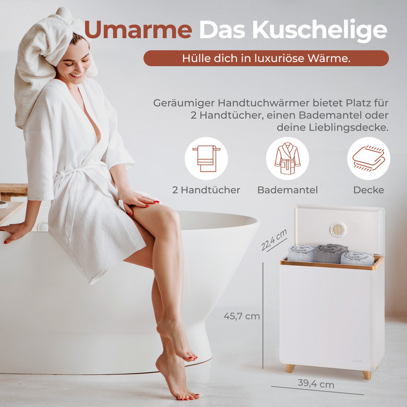 Frau in Bademantel neben Badewanne, daneben Handtuchwärmer mit Tüchern.