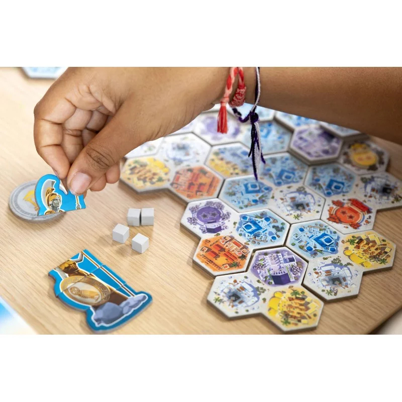 Una mano posiziona una tessera di gioco di un uomo in armatura su un tabellone di tessere esagonali.