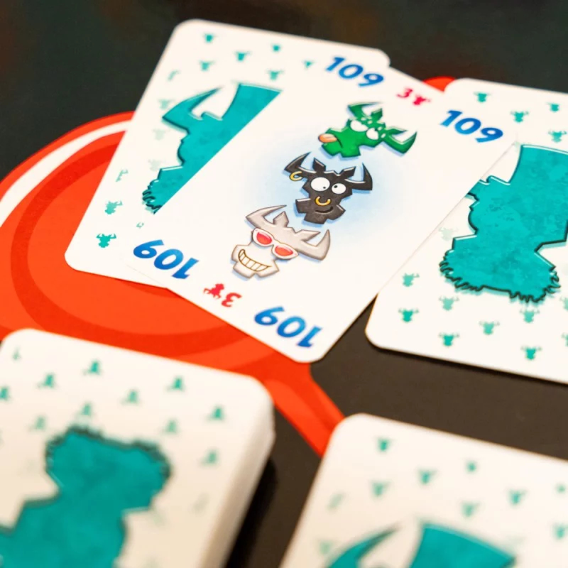 Spielkarten mit Cartoon-Monstern und Zahlen auf einem roten Kreis.